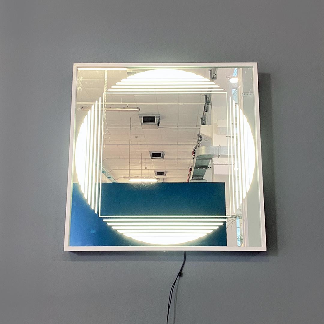 Italian modern neon backlit square mirror with semi-transparent decoration on the glass by Gianni Celada for Fontana Arte, 1970s.
Backlit neon mirror, square shape with container frame in white metal and mirror with concentric circular and