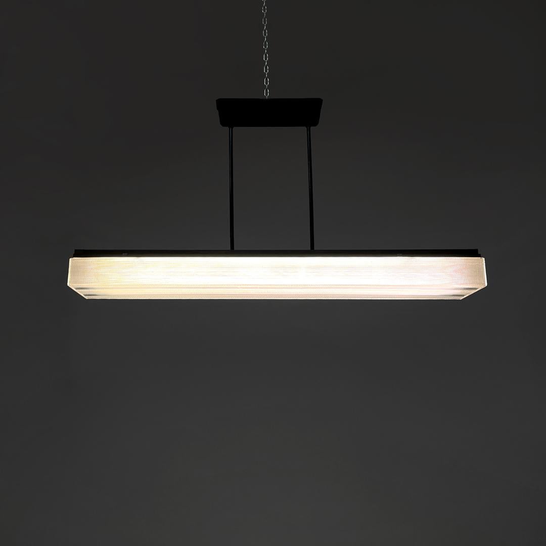 Italian modern neon ceiling chandelier with black metal structure, 1980s
Neon chandelier with rectangular base. The lampshade is made of transparent plastic with a geometric texture, on the sides there are two metal studs which act both as