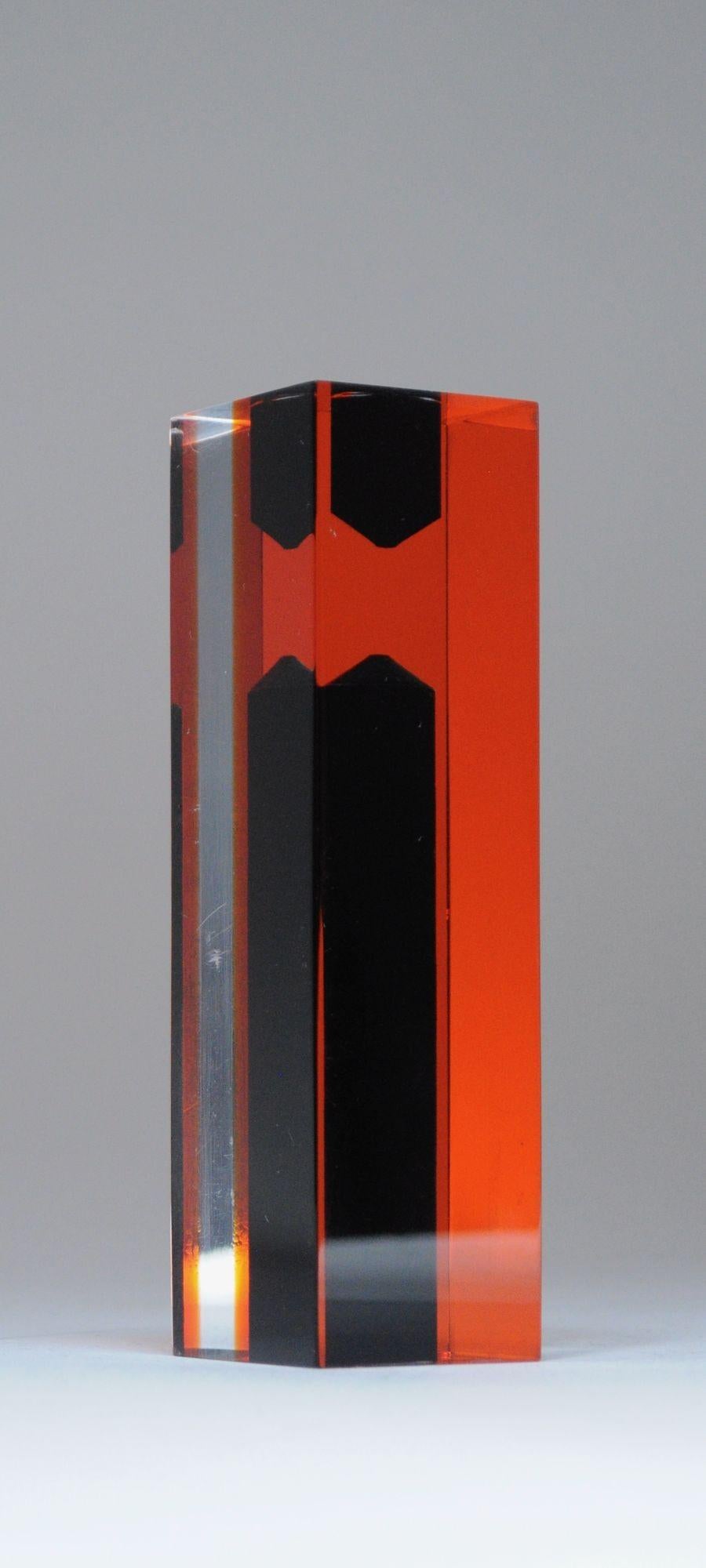 Llamativo florero/portavelas de lucite con facetas transparentes y naranjas que albergan recipientes negros para flores/velas según el lado que esté en posición vertical (ca. 1970, Italia - al estilo de Lugi Massoni para Guzzini).
Pieza versátil con