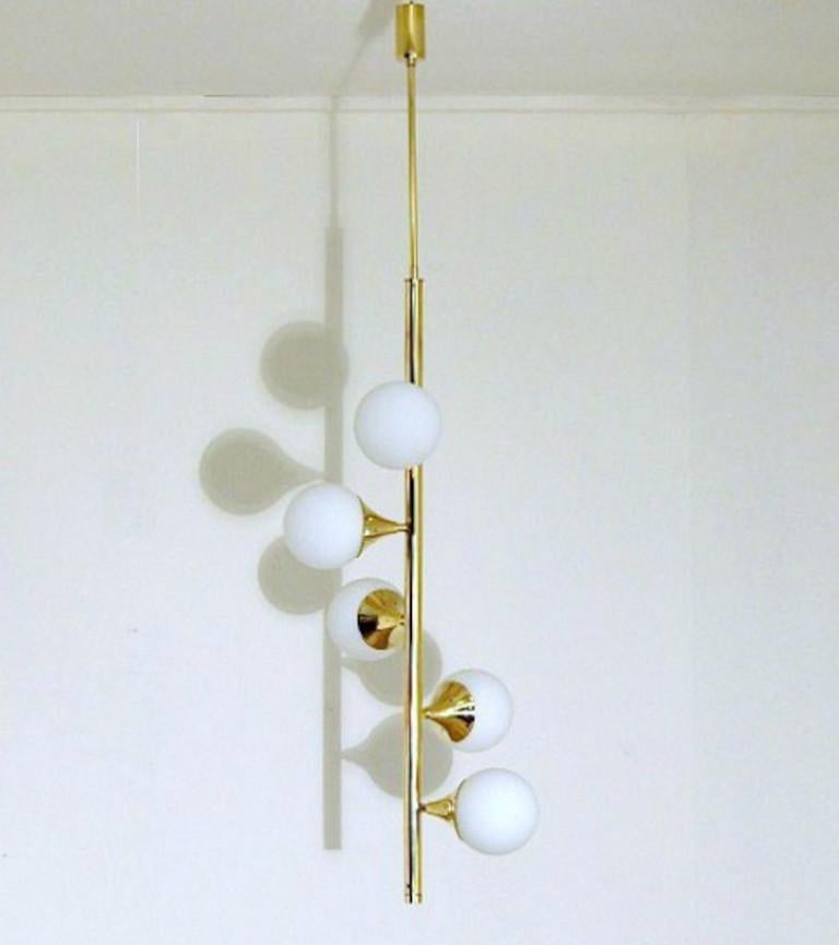 Elegant sculptural chandelier shown in un-lacquered natural brass with opaline milky glass globes fabricated in Italy by Fabio Ltd. 

This is a modern, contemporary interpretation of a classic chandelier, strongly influenced by Italian Mid-Century