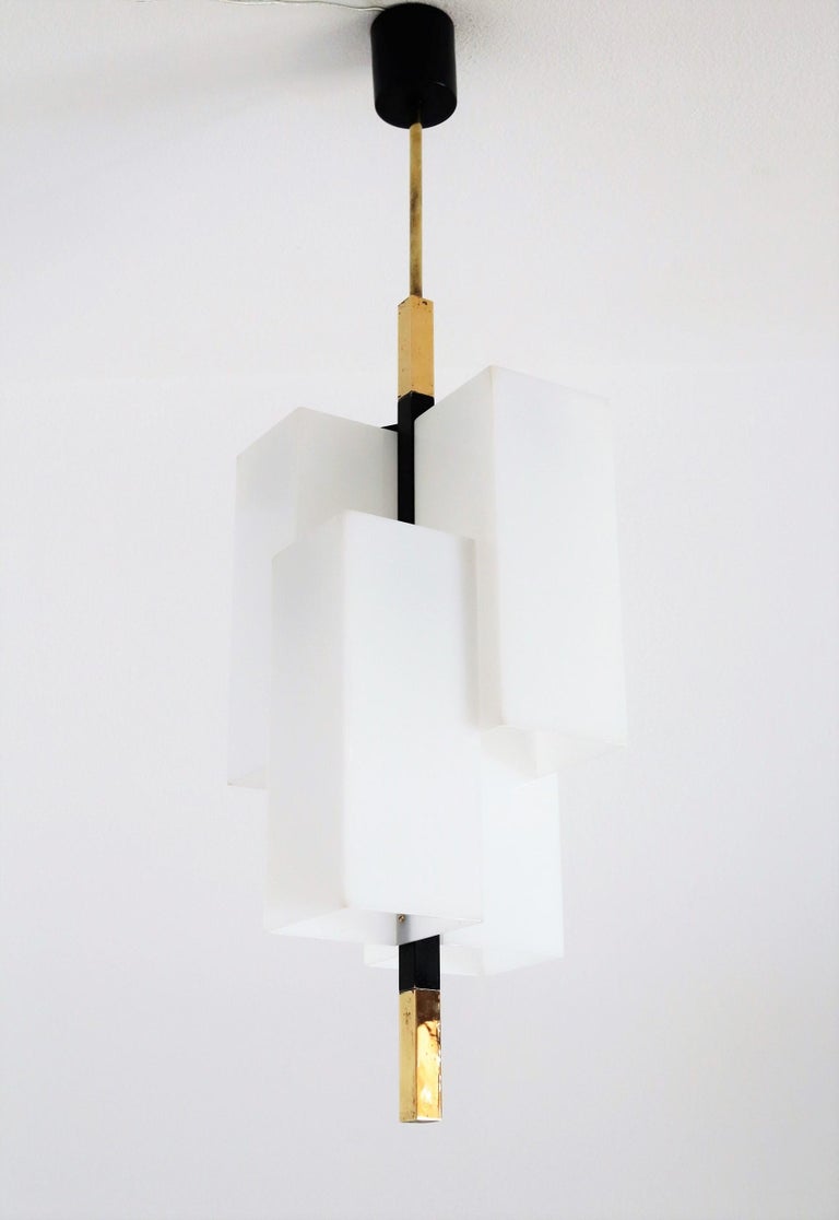 Italian mid-century pendant lamp or chandelier manufactured from Stilux Milano in the 1970s.
The pendant light is made of four square acrylic lampshades which are mounted to the center brass rod in different heights.
In each of the lampshades is