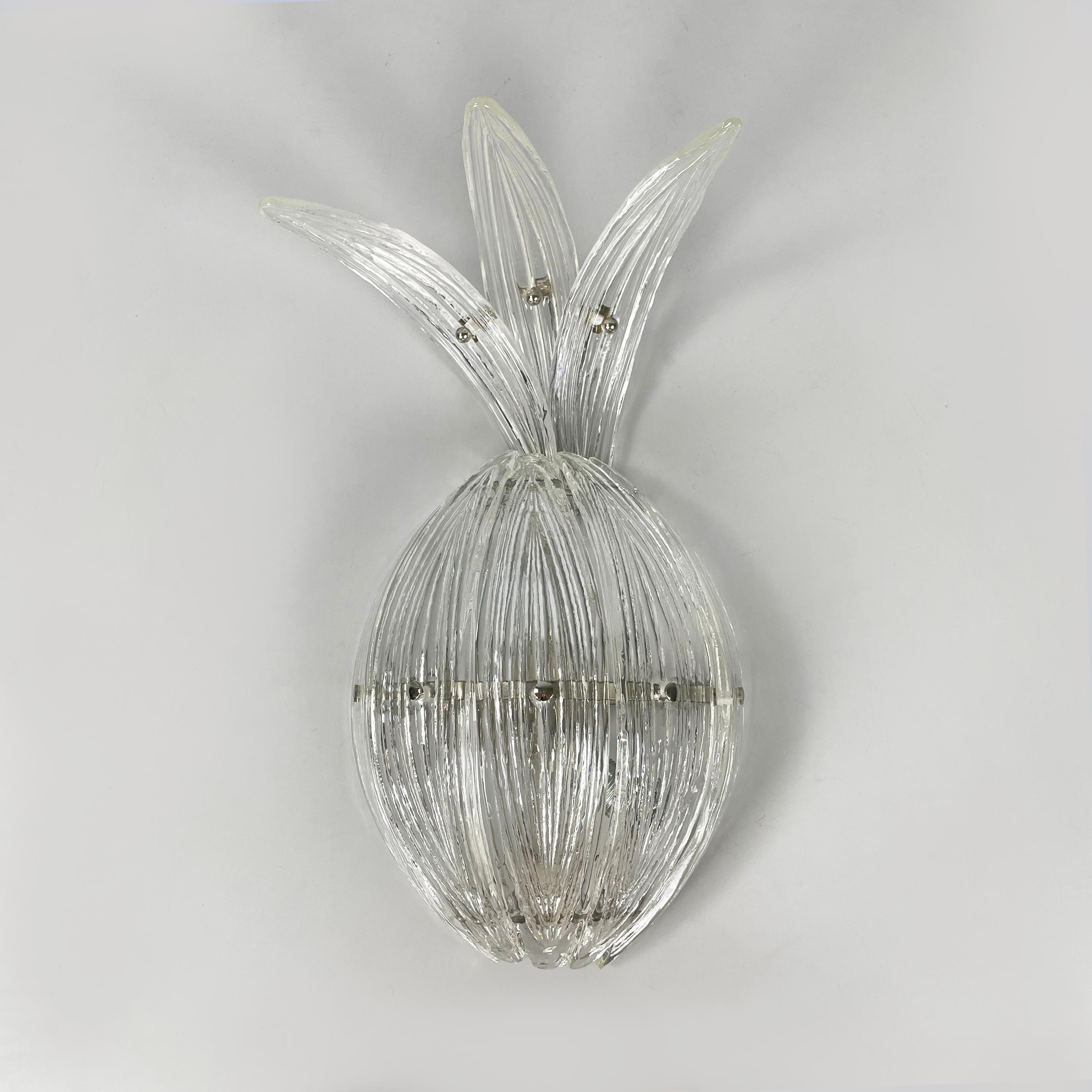 Lampada da parete moderna italiana a forma di ananas in vetro scanalato e metallo, anni '80
Lampada da parete a forma di ananas in vetro trasparente. Il diffusore a base ovale è costituito da una combinazione di lastre di vetro curve e scanalate.