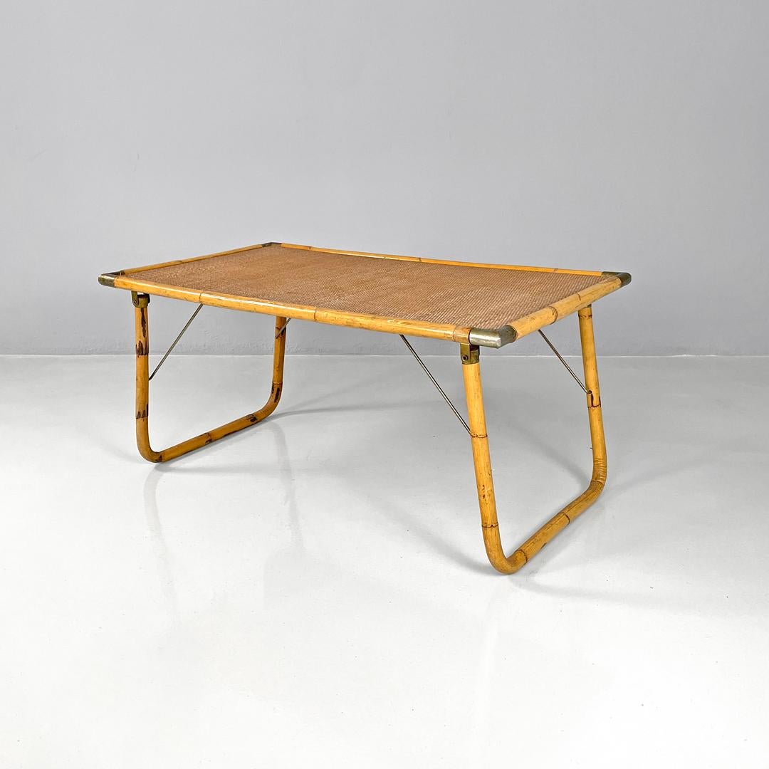 Italian modern rattan and brass folding table by Dal Vera, 1970s
Folding rattan table with rectangular top. The profiles of the table and the legs are made of bamboo, the top is woven and has the corners covered with brass parts that act as