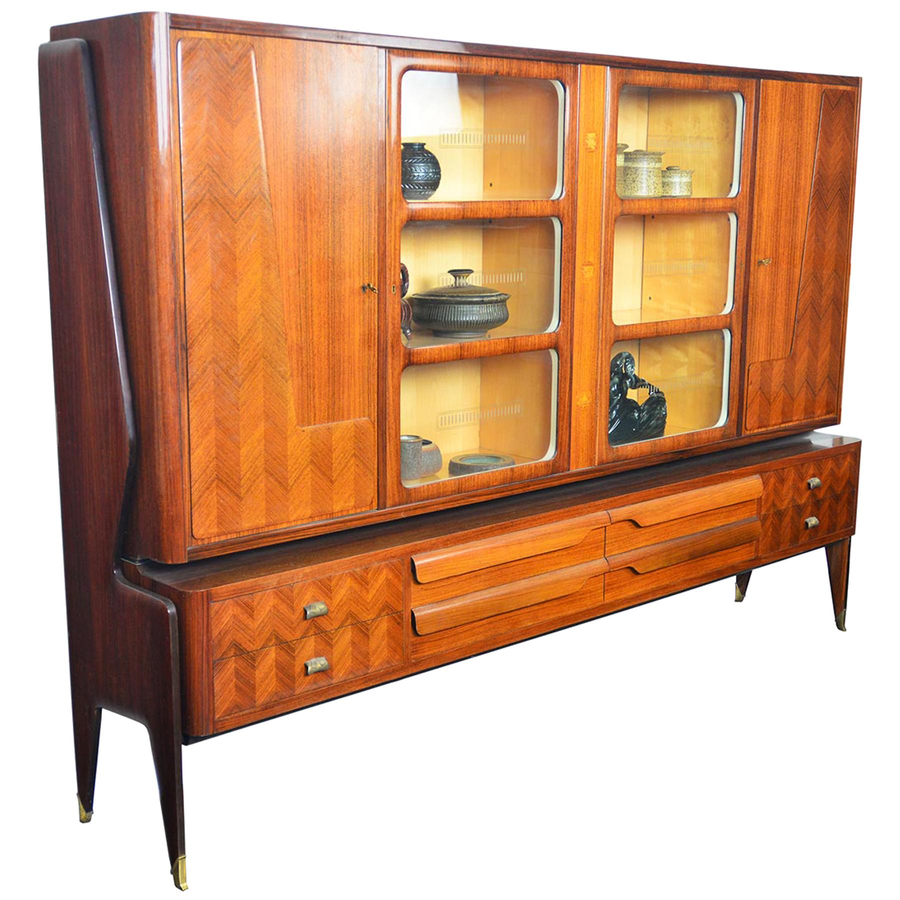This grand Italian modern bookcase by Vittorio Dassi offers stunning craftsmanship and delightful design details throughout. The large upper hutch offers four locking doors. The interior cabinets feature glass doors with original etched detailing.