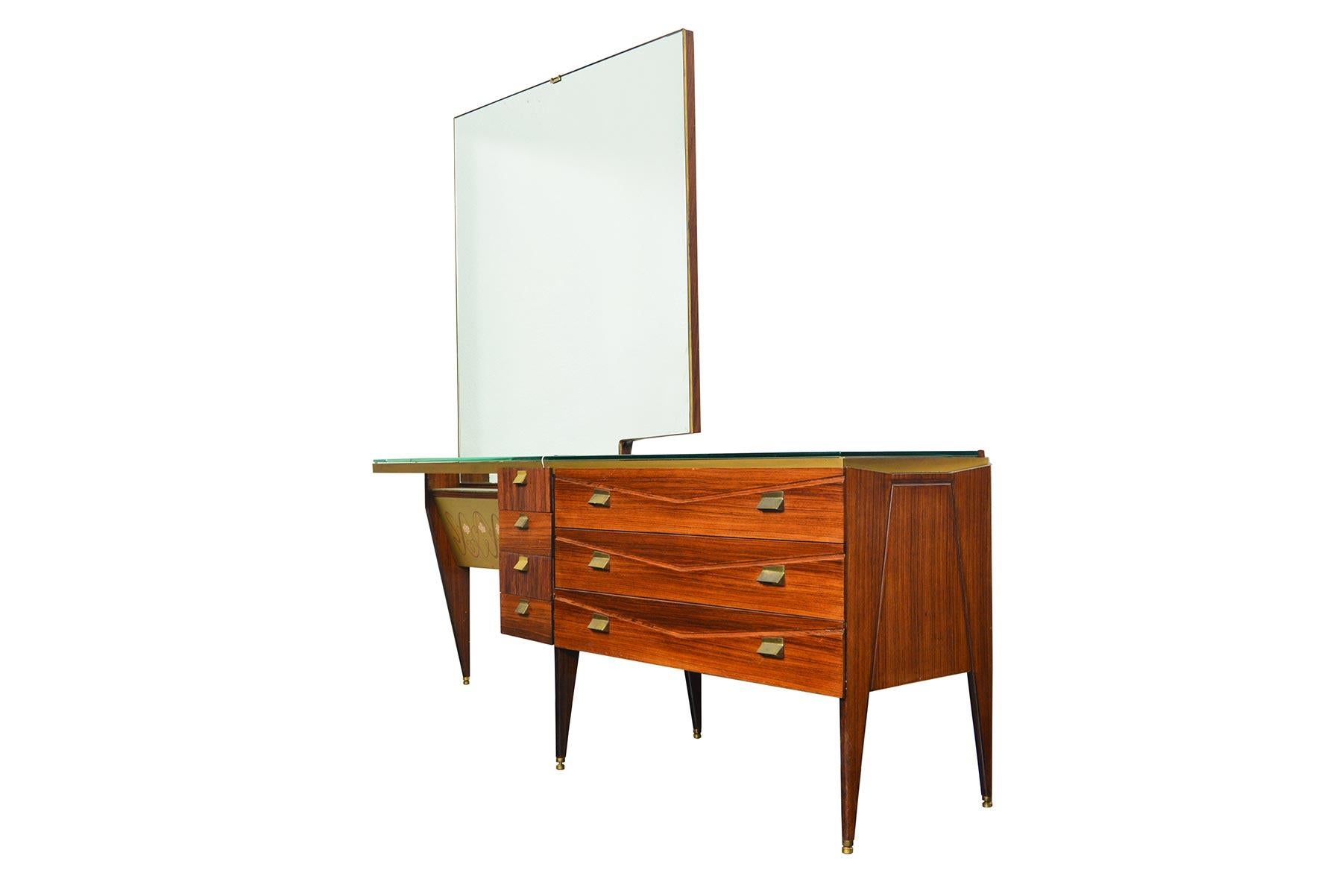 Stunning in design and execution, this Italian modern vanity was crafted by Vittorio Dassi in the 1950s. Cased in rosewood, this vanity is supported by five legs capped in brass. Three large drawers are adorned with brass pulls and feature a routed