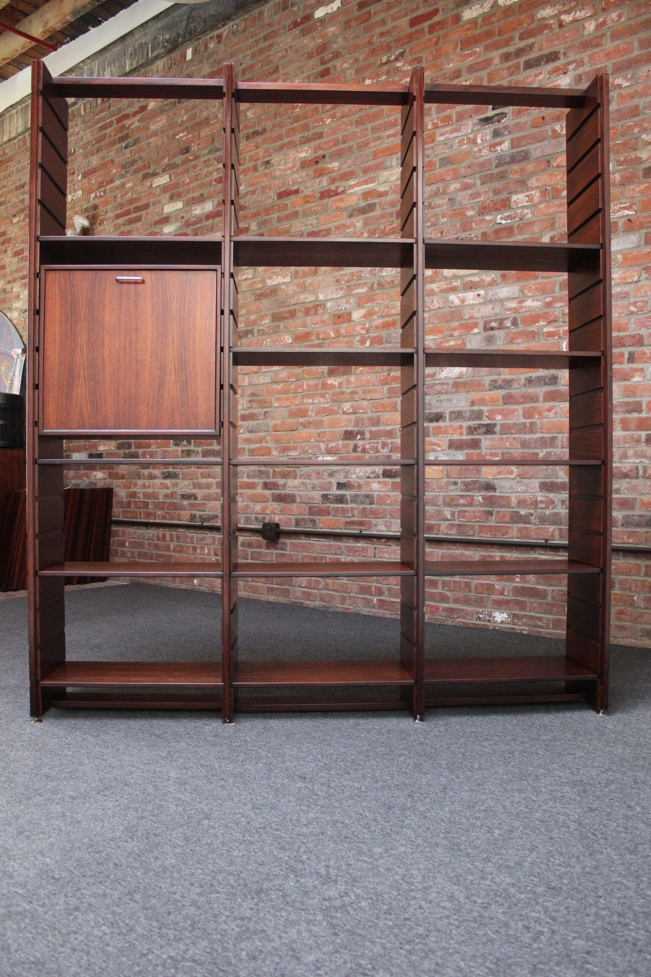 Model 540 modular bookcase designed by Gianfranco Frattini for Bernini (ca. 1960s, Italy).
Uncommon rosewood example composed of four vertical slatted-rails creating three bays including 14 shelves and one drop-down storage/bar cabinet with a