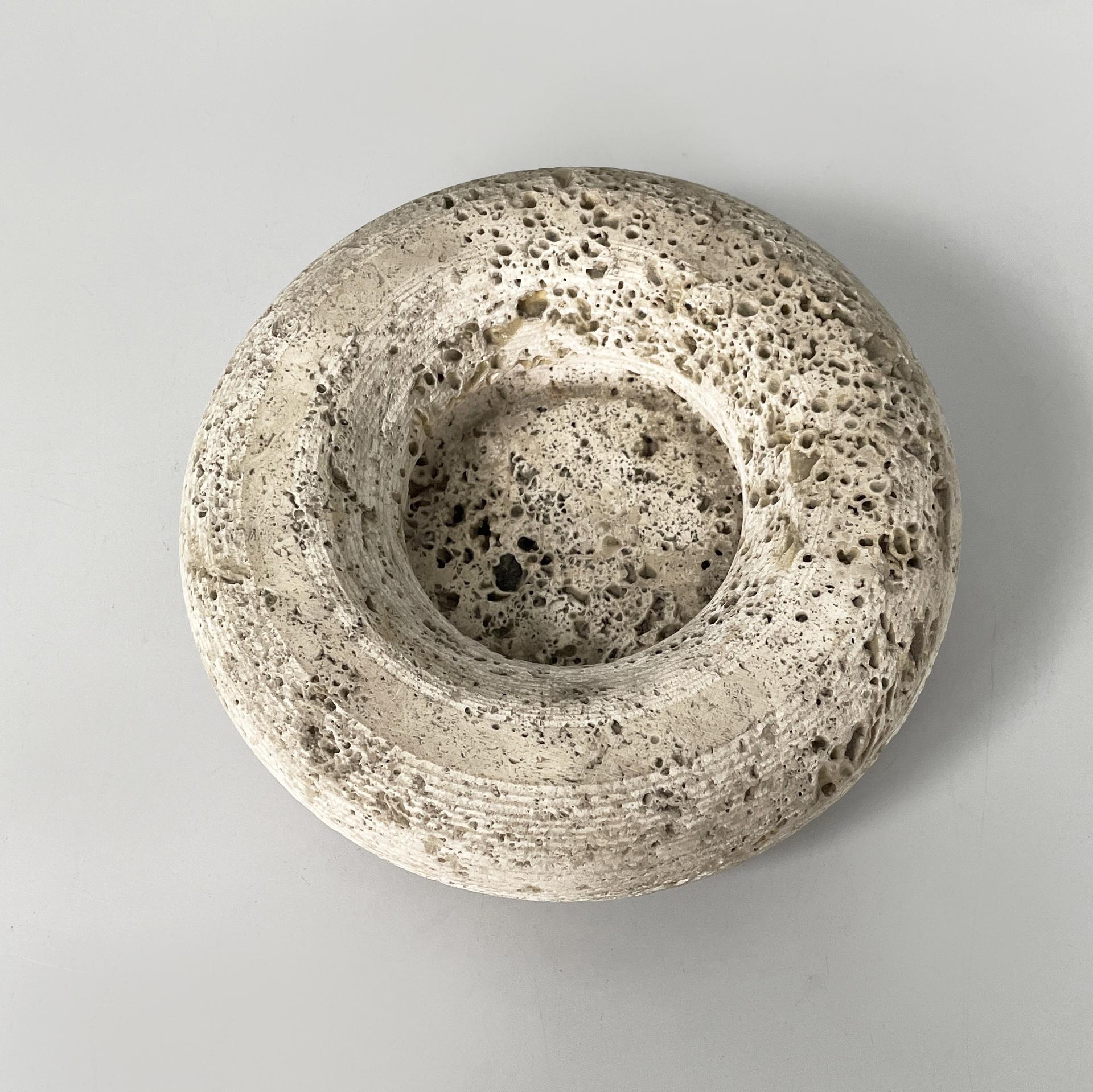 Italian modern round ashtray in travertine, 1970s
Round-based table ashtray entirely in travertine. The thick profile features small decorative grooves. There are three square feet at the base. It can be used as a decorative bowl or as a pocket