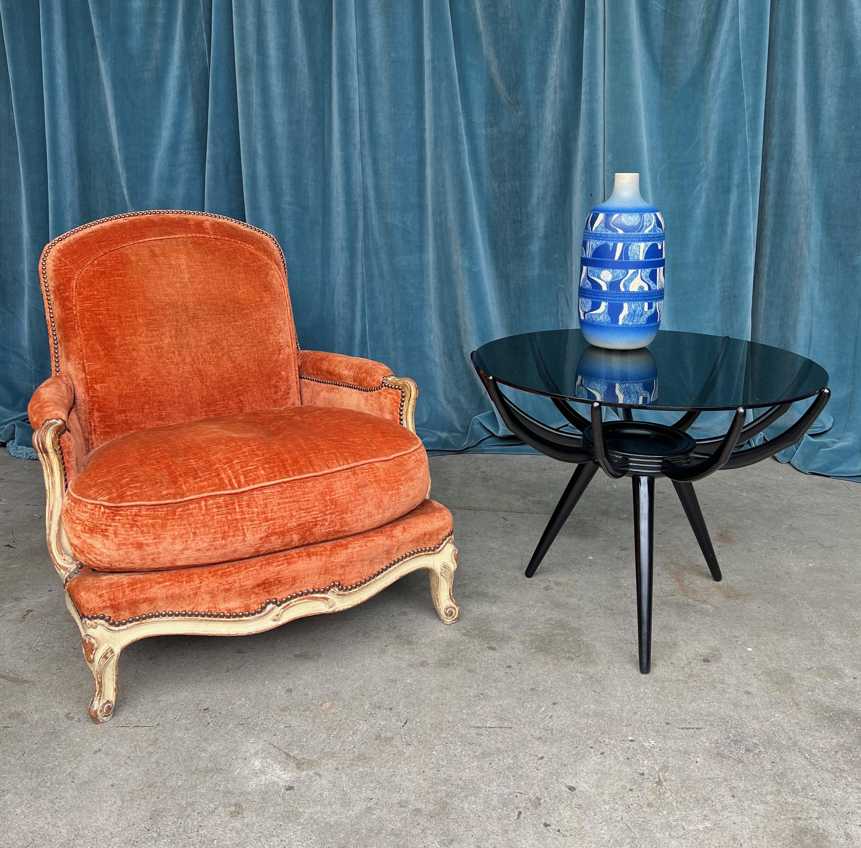 This Italian 1960s modern round end table presents a chic blend of black and grey, with a sleek glass top resting on a tripod base. Although the piece is attributed to Carlo De Carli (1910-1999), it bears no attribution marks. De Carli was not just
