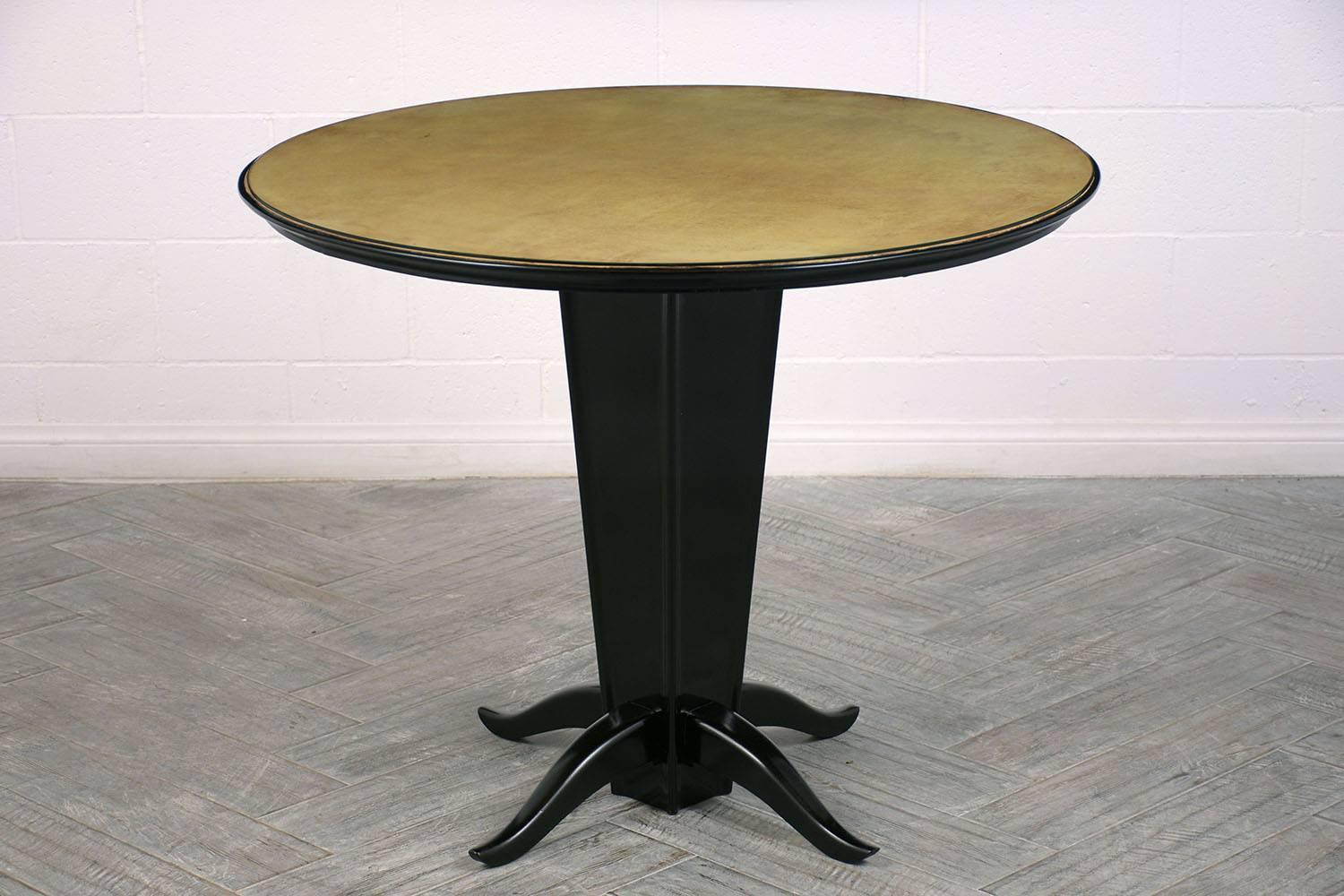 This 1930s Italian modern-style center table is made of mahogany wood with a leather top. The mahogany pedestal base has four stabilizing feet with curved ends and an ebonized and lacquered finish. The original leather top is dyed a light green