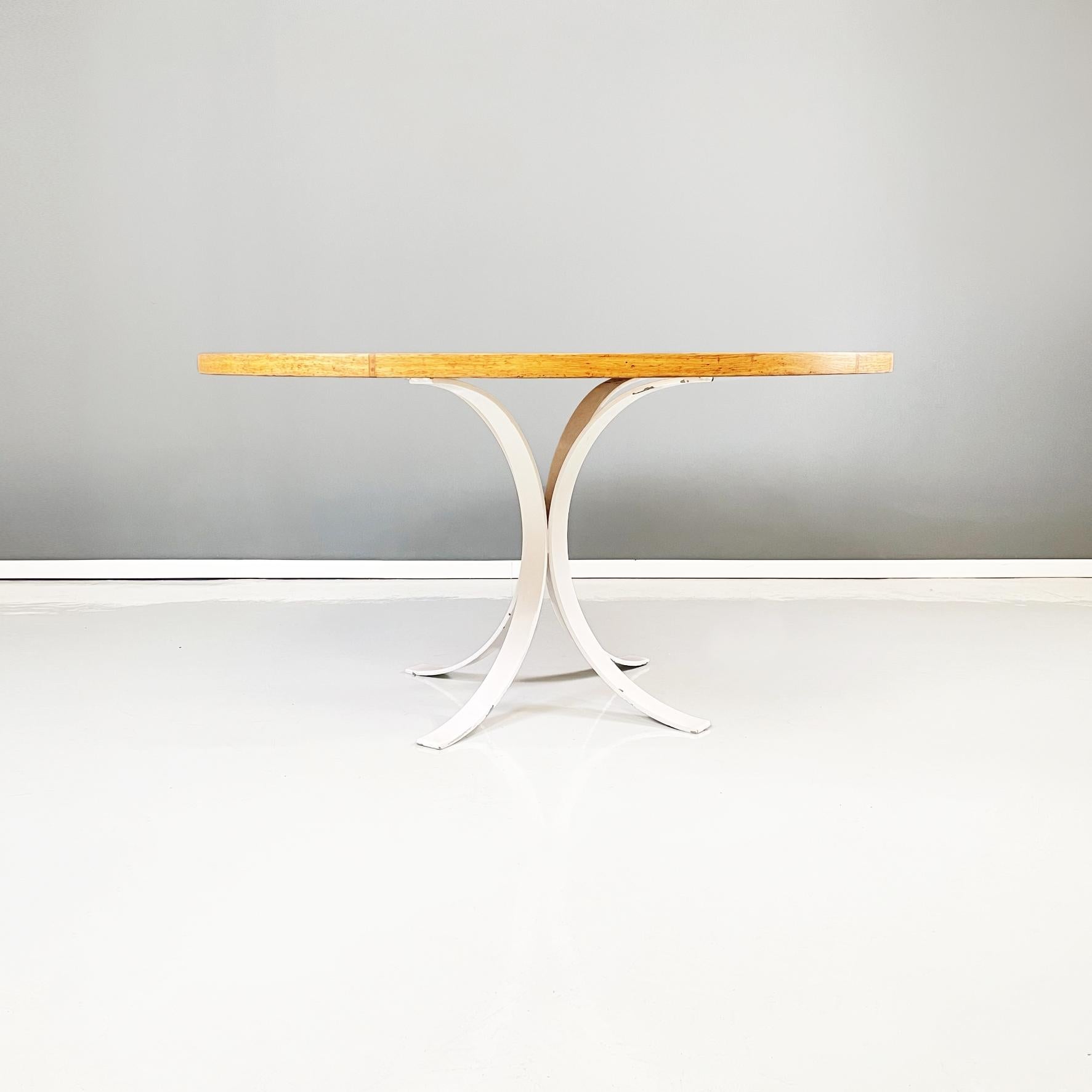 Italian modern Round dining table in white metal and solid wood, 1970s
Dining table with round thick top of large diameter in solid wood. The white painted metal structure, on which the top rests, narrows in the center and widens at the bottom,