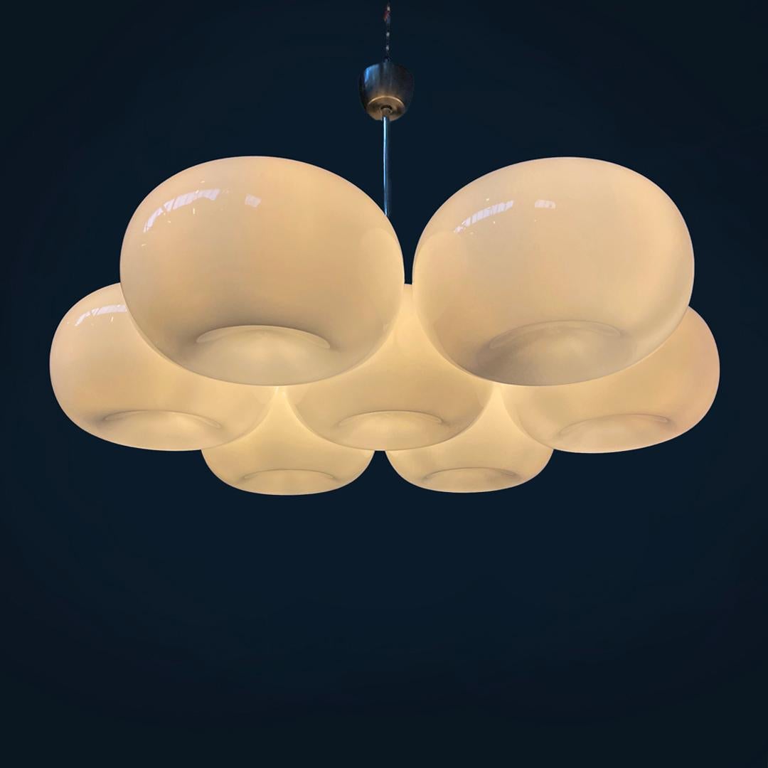 Lampadario moderno italiano rotondo in vetro opalino e metallo, anni '70
Lampadario con sette paralumi in vetro opalino. Ogni paralume cilindrico ha una cavità sul fondo.
La struttura del lampadario è in metallo con uno stelo centrale e sei bracci,