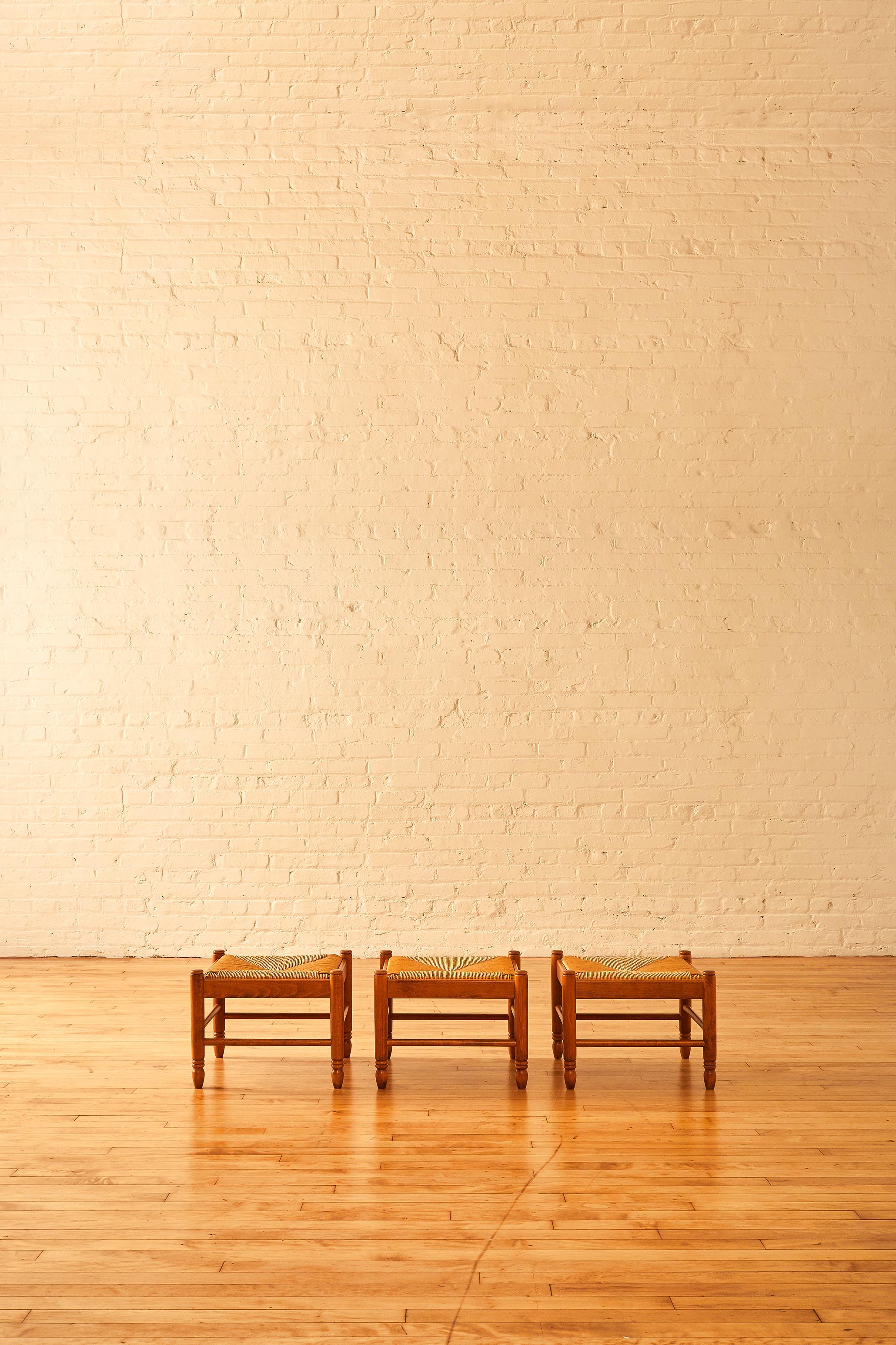 Italian made rush ottoman or stool in the manner of famed French architect, Charlotte Perriand. Excellent condition for age, these stools are made of rush seat and an oak wood base. Made in Italy, these stools are impeccably preserved throughout the