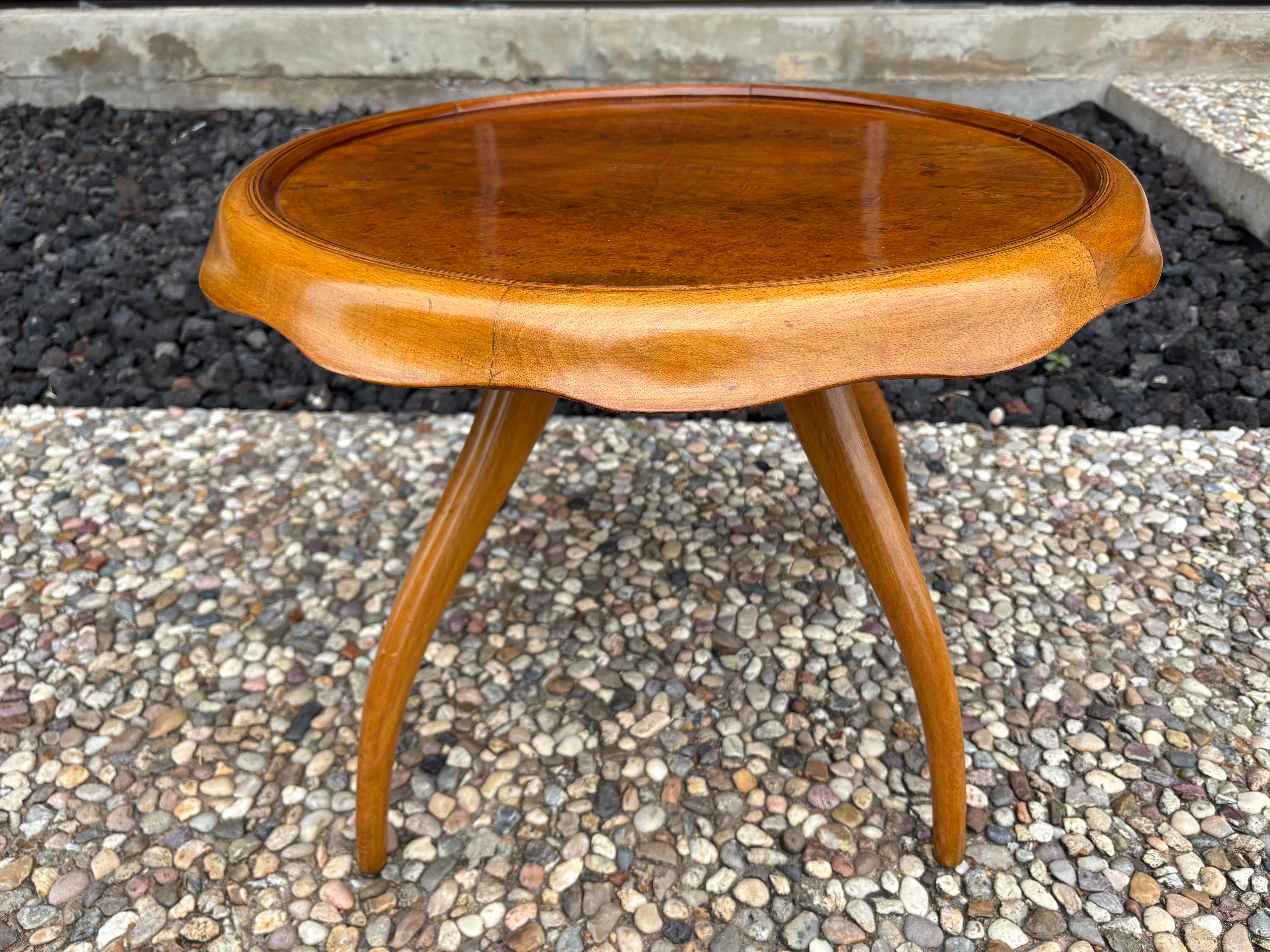 Italian Modern Sculptural Table By Osvaldo Borsani.
Offered is a lovely Italian mid century modern coffee table or side table in the manner of Gio Ponti. This versatile round table of mixed woods has a draped apron around the top with splayed