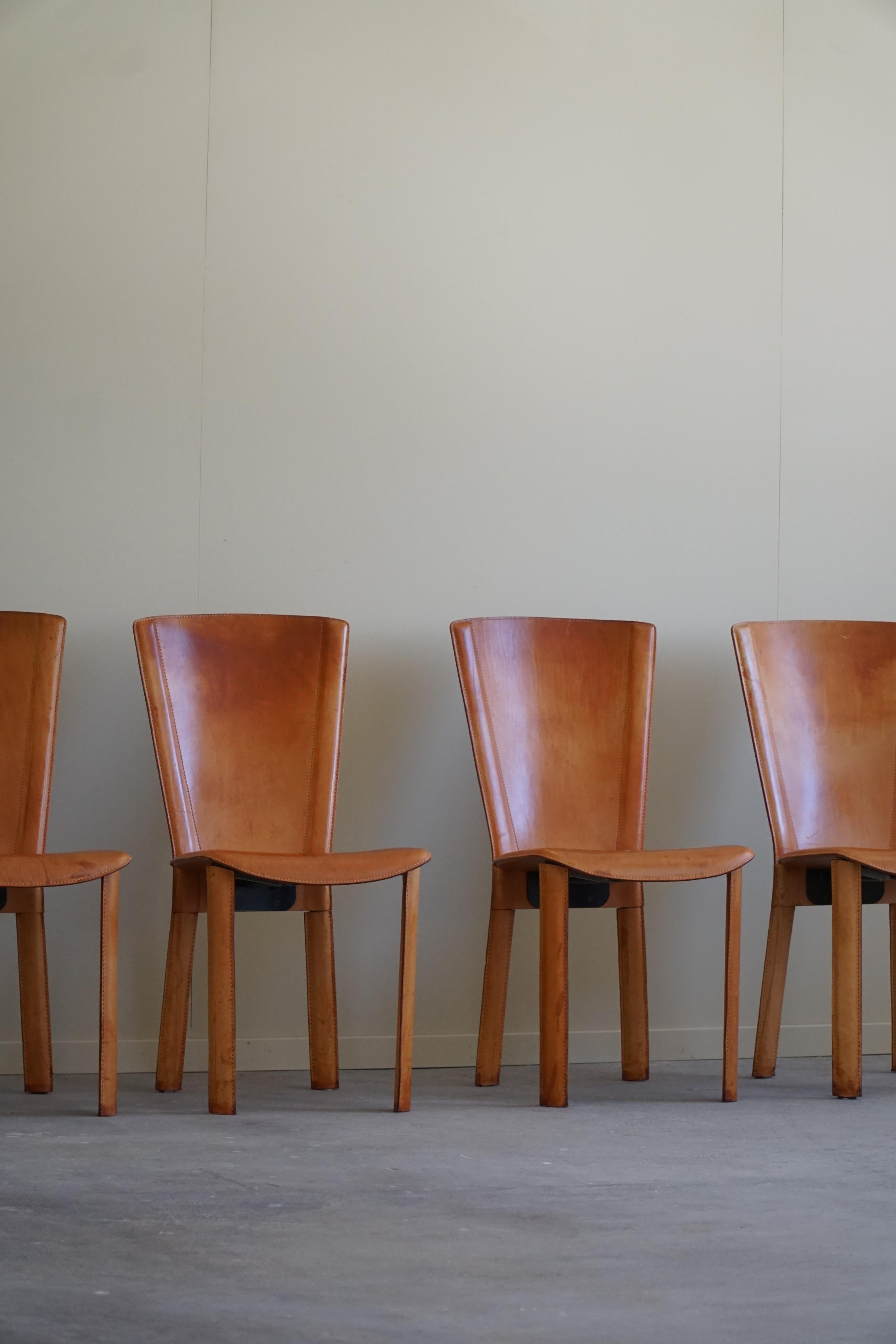 An amazing set of 4 dining chairs in a deep cognac colored leather. Made in Italy, attributed to the Italian architect Mario Bellini. Made in the 1970-1980s. 

Such beautiful lines and a warm patina that complement the overall impression of this