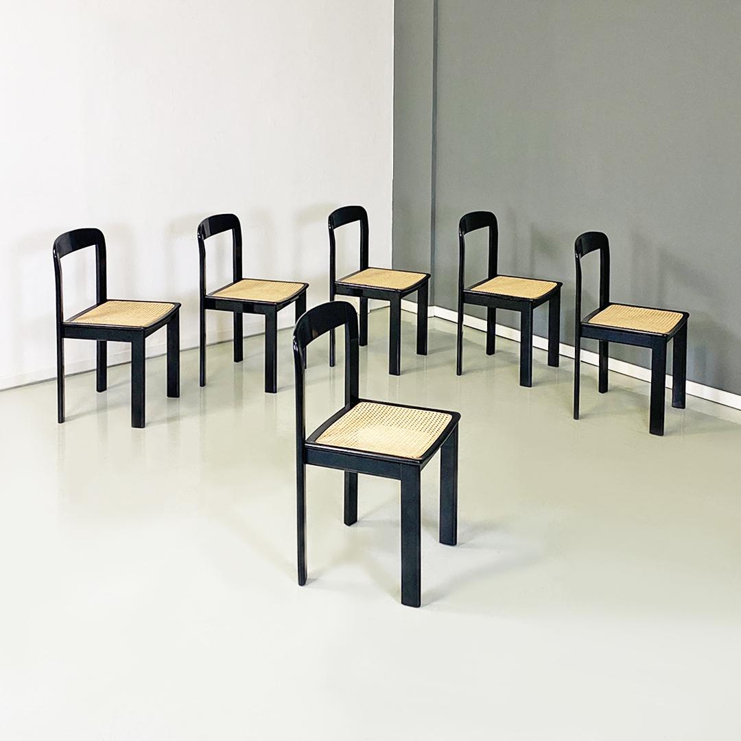 Ensemble moderne italien de six chaises en bois laqué noir et en paille de Vienne, années 1980.
Ensemble de six chaises en bois laqué avec pieds avant décalés par rapport aux pieds arrière, dossier de forme arrondie et assise en paille de Vienne,