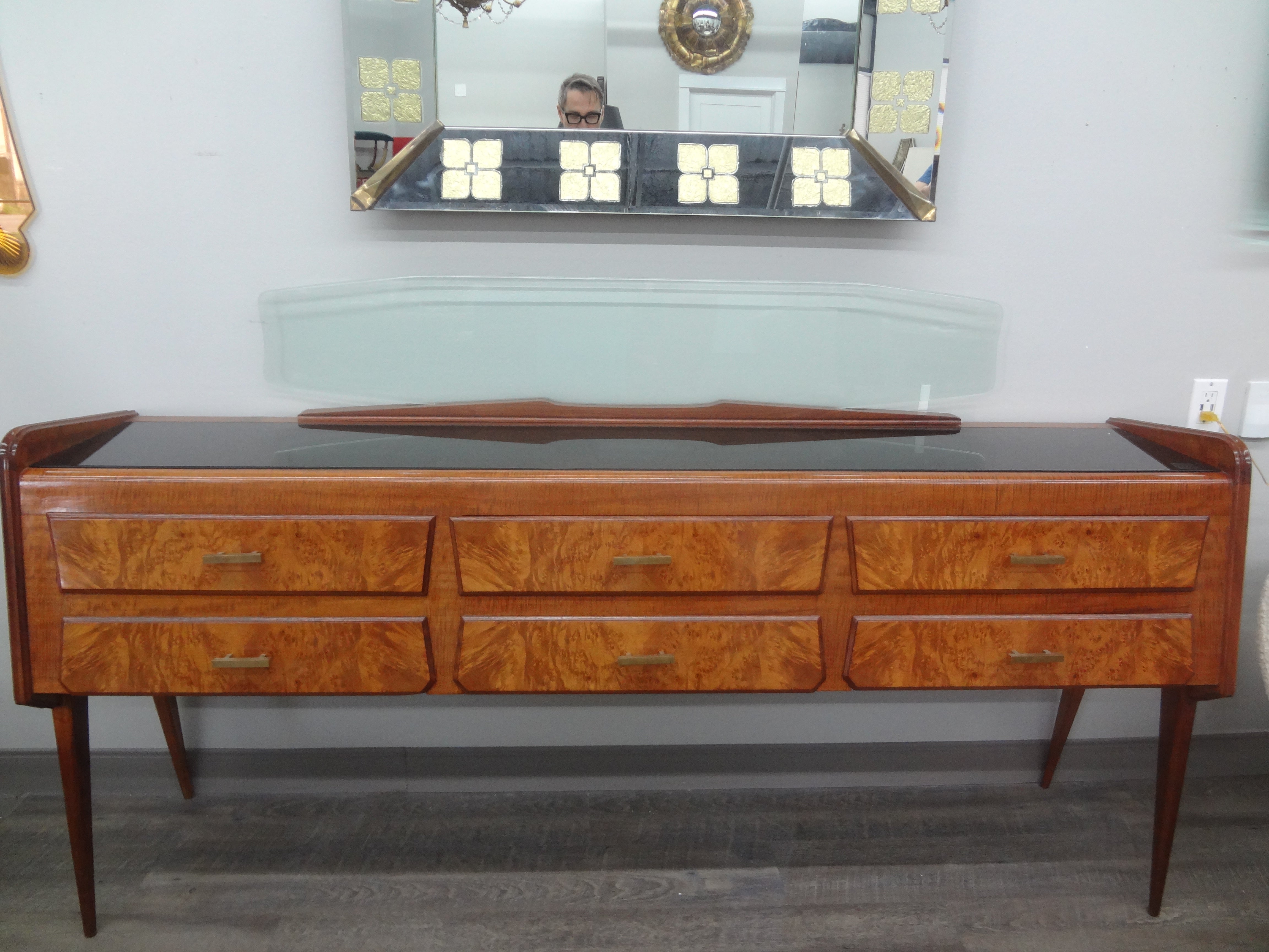 Italian Modern credenza after Ico Parisi.
This stunning Italian Mid-Century Modern credenza, commode or console table has shapely legs, six drawers with brass hardware, a black opaline top and an interesting clear glass backplate.
This outstanding