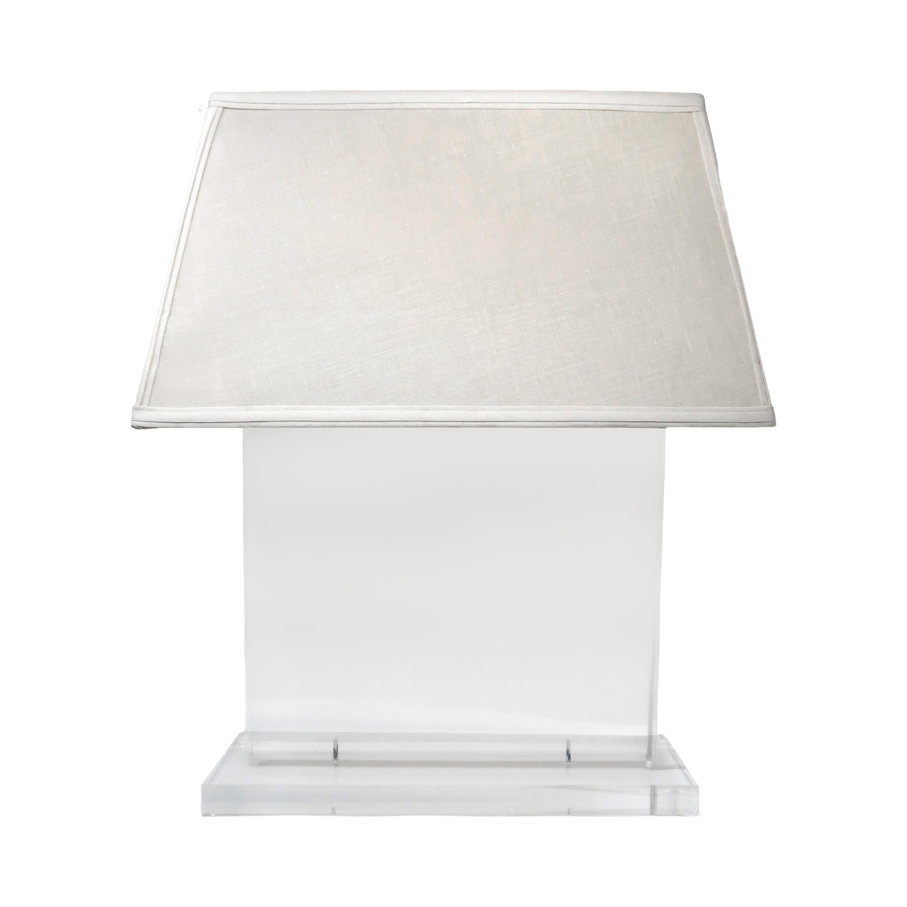 A beautiful 1970s Italian Modern lucite table lamp with transparent base, slim rectangular body, and rectangular angled fabric-covered shade. Fantastically minimalist with a slim profile that glows when the lamp is turned on.

In very good