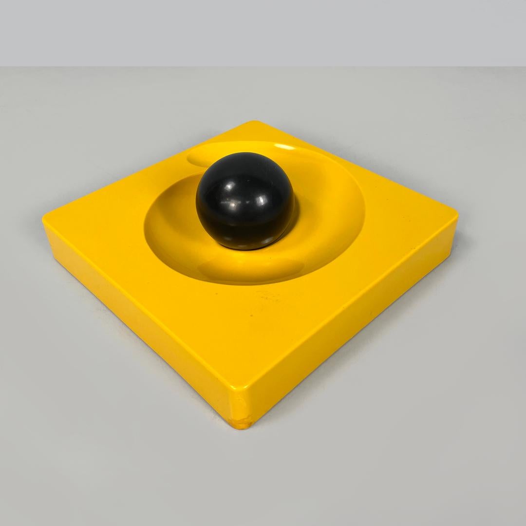 Posacenere moderno italiano quadrato giallo Spiros Eleonore Peduzzi Riva Artemide anni '70
Posacenere mod. Spiros di forma quadrata. La struttura è in plastica gialla, sulla parte superiore c'è una spirale concava su cui scorre una sfera di plastica