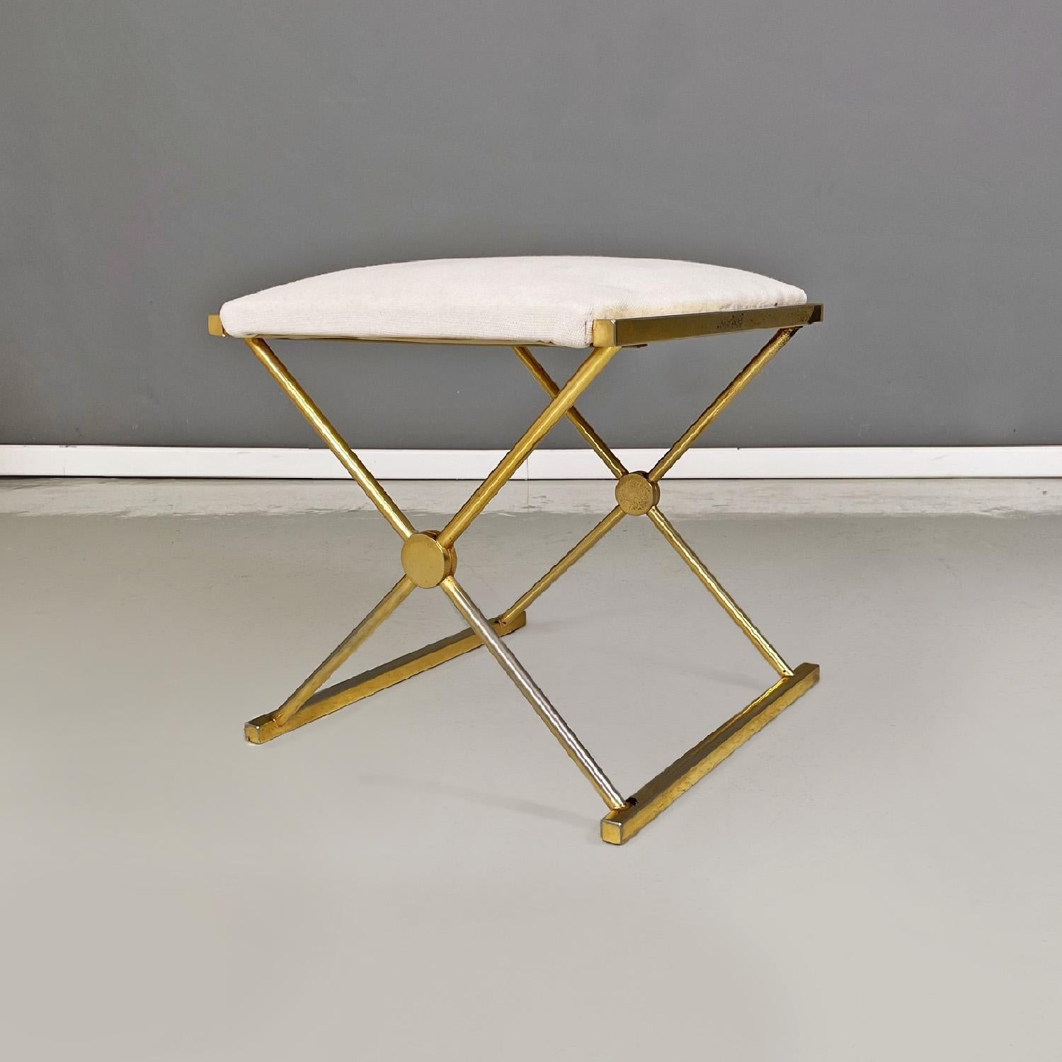 Italian modern Stools in golden metal and white fabric, 1980s
Set of two stools with padded rectangular seat covered in white fabric. The structure, in metal with a golden finish, crosses on two sides to form the legs and the floor