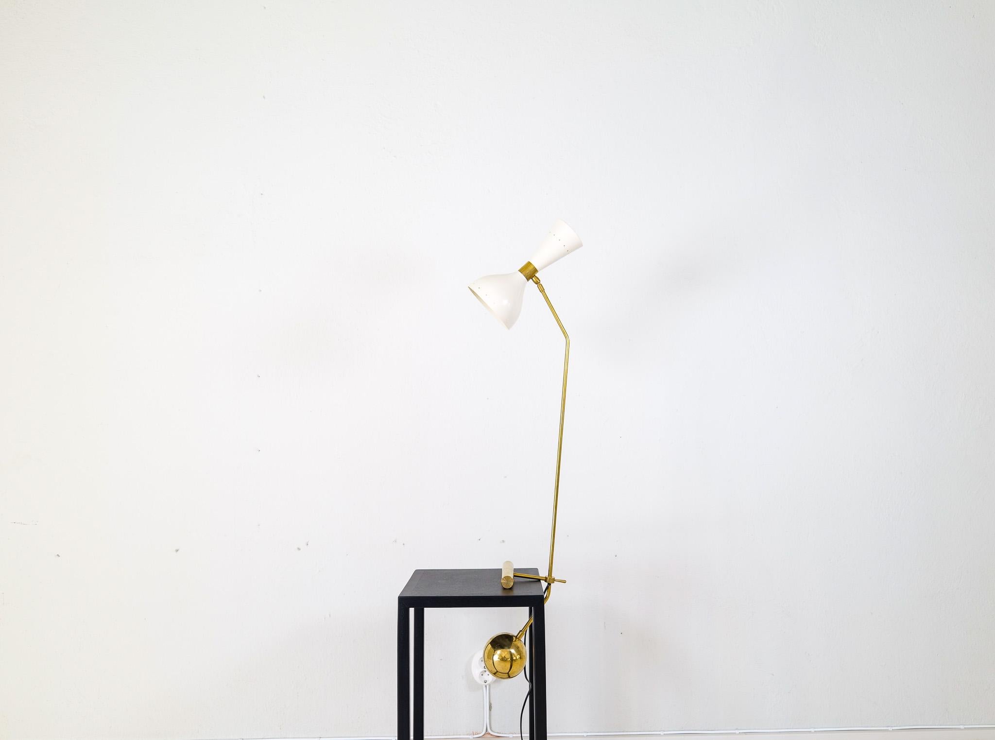 Wonderful Italian modern table lamp. The lamp has a weight in brass that works as both as a counter weight and stylish part of the lamp. Made with brass and painted sheet metal. Lampshade is adjustable and can light in different directions. The