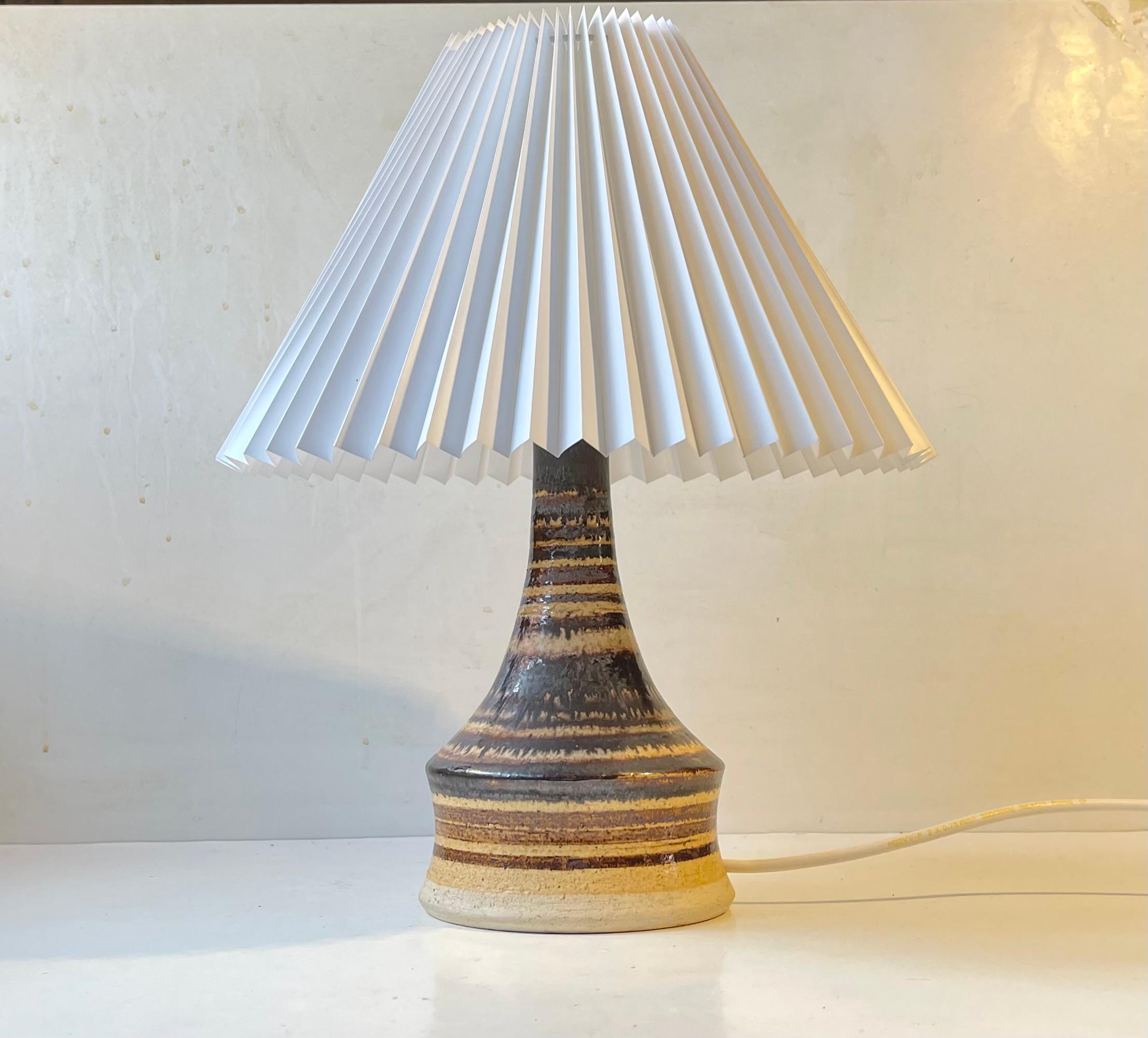 Italian ceramic table light decorated with stripes in earthy glazes. It has no markings besides a handwritten Italy to its inside. Stylistically it is very similar to lamps by Danish Tue Poulsen and Einar Johansen. It is mounted with a new white