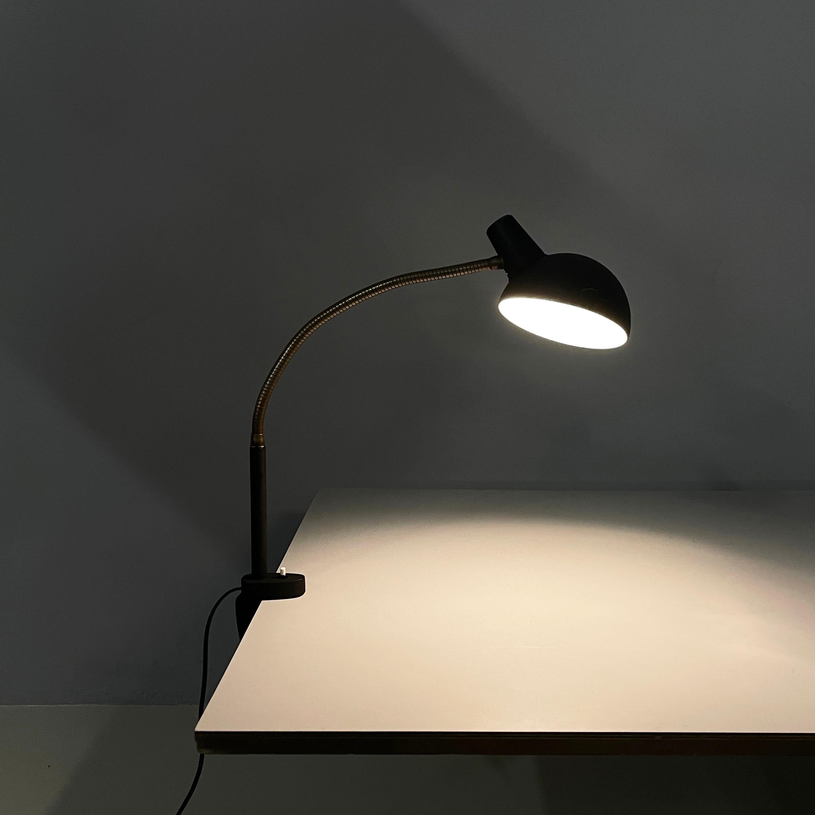 Lampe de table moderne italienne avec pince en métal noir et laiton, années 1970.
Lampe de table avec pince et diffuseur réglable en forme de dôme en métal peint en noir. La structure articulée est en laiton avec une pince métallique peinte en noir