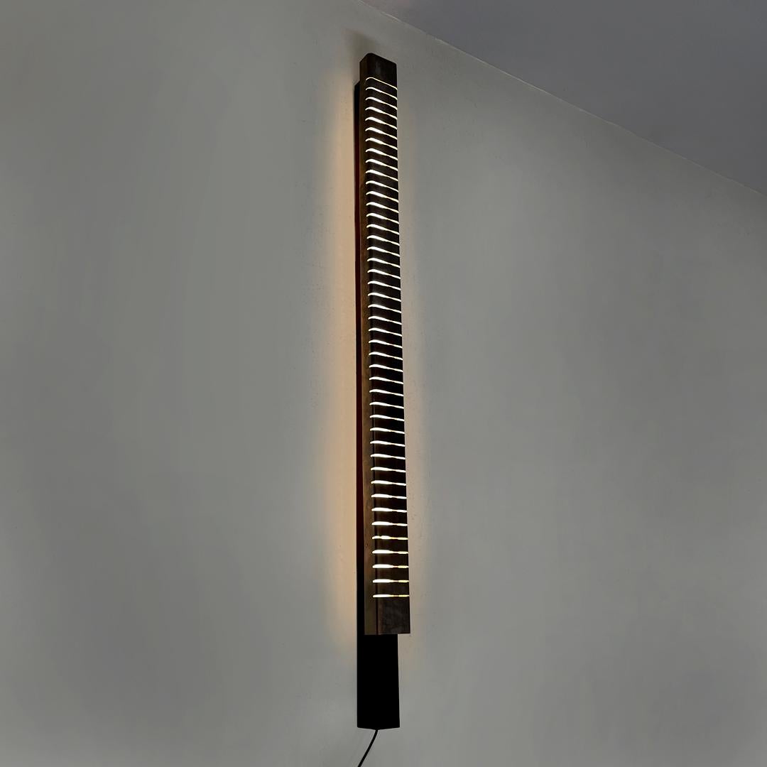 Applique haute moderne italienne en métal chromé par Lamperti, années 1970.
Applique allongée à base carrée. La structure ressemble à une colonne et est faite de métal chromé avec une série de gravures à intervalles horizontaux réguliers. La base