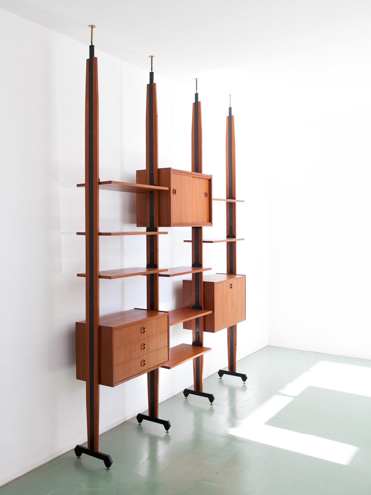 A modern bookcase, manufactured in Italy in the 1950s.

The mounting of this bookshelf is with pressure between the floor and the ceiling.
This wall unit is made up of a cabinet with sliding doors, a chest of drawers with three drawers and a flap