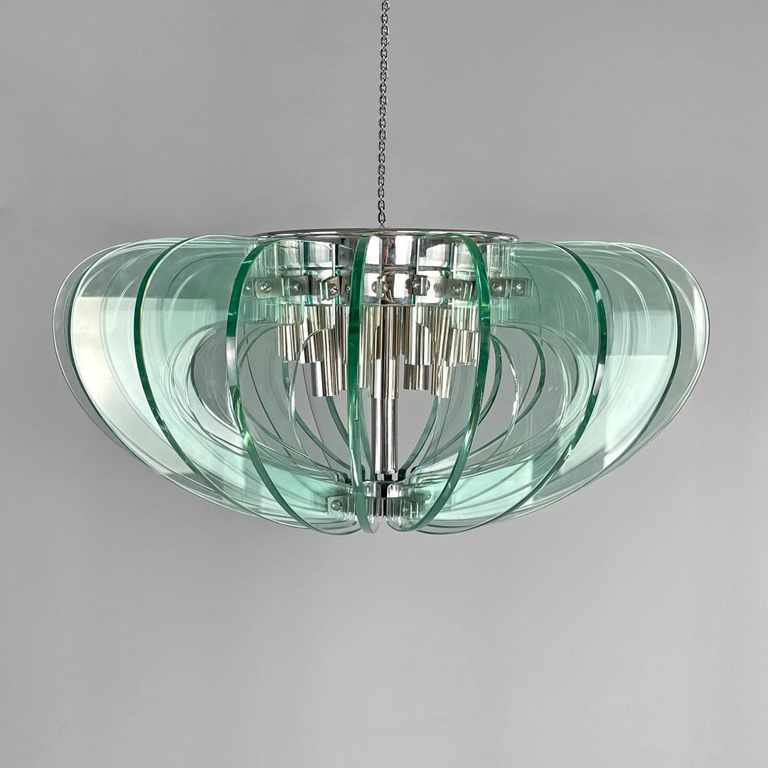 Lampadario moderno italiano in vetro trasparente arrotondato e metallo cromato, anni '70
Lampadario in vetro a base rotonda. Il paralume è composto da venti lastre di vetro trasparente semicircolari con linee curve che si sviluppano intorno alla