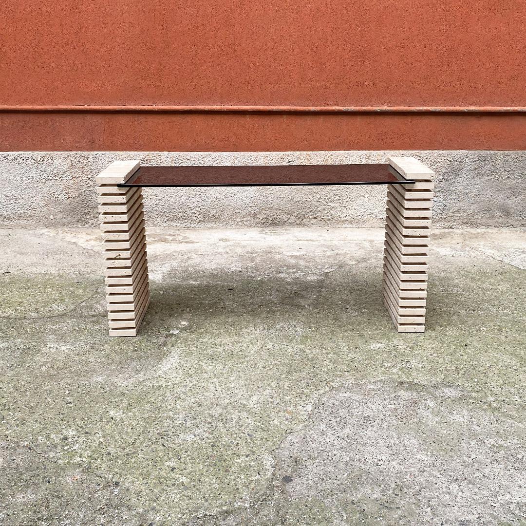Italian modern travertine and adjustable smoked glass consolle, 1970s
Console with side legs in travertine, with parallel grooves on all sides, with smoked glass shelf with adjustable height.
1970s.
Good condition, glass with chipped