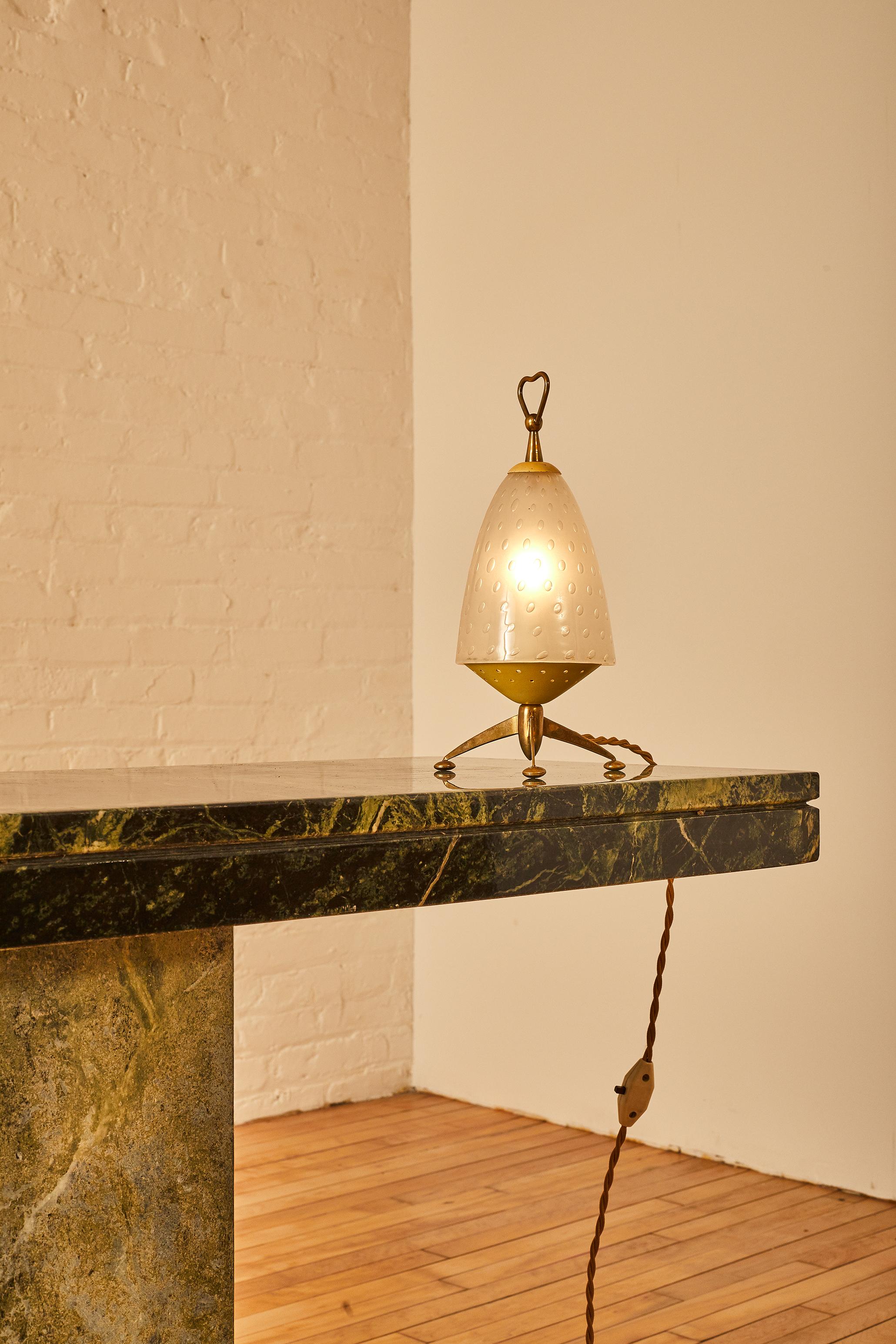 Italian modern table tamp featuring a glass shade and brass tripod legs. 

