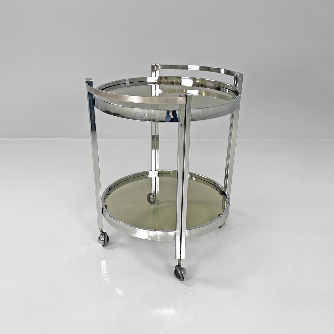 Italian modern two tops chromed metal and smoked glass cart with wheels, 1970s
Round base trolley. The structure is in chromed metal, with the four legs having a rectangular section and two bands that make up the two floors, which are in smoked