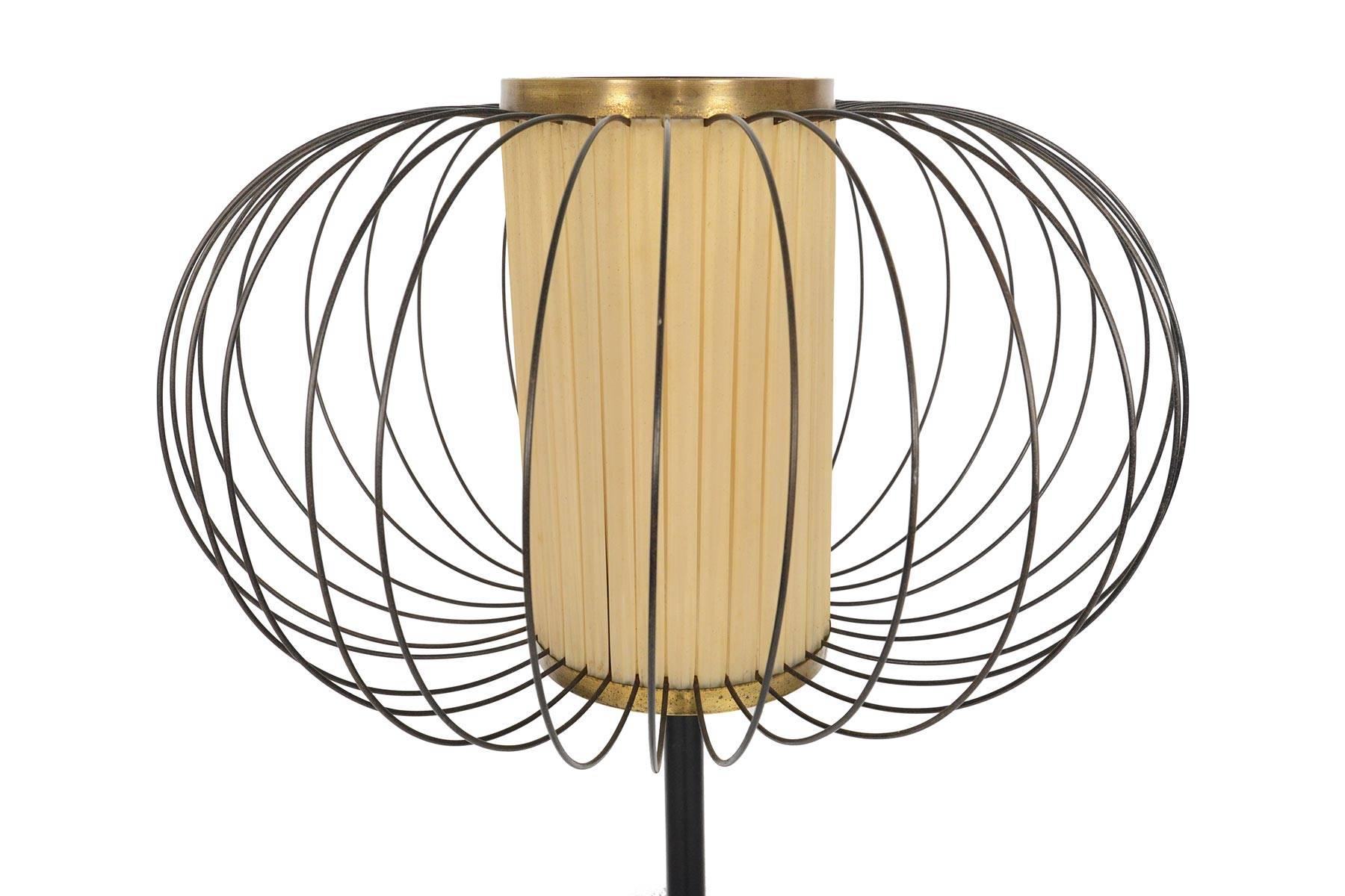 This striking Italian modern floor lamp not only offers a beautiful warm glow, but is designed with a magnificent sculptural appeal. A wire cage surrounds a parchment- toned ribbon shade. The ebonized steel shaft stands on a weighted marble base. In