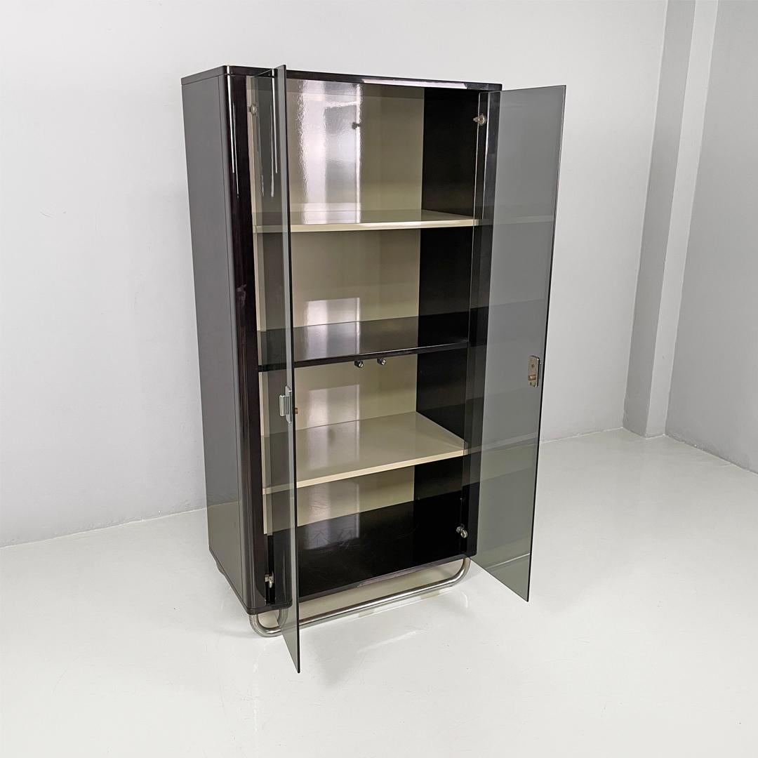 Italian modern wooden black lacquered wardrobe, 1970s
Wardrobe made entirely of black lacquered wood with double smoked glass doors.
Inside, there are four compartments divided by two black and two gray shelves.
The curved legs and handles are