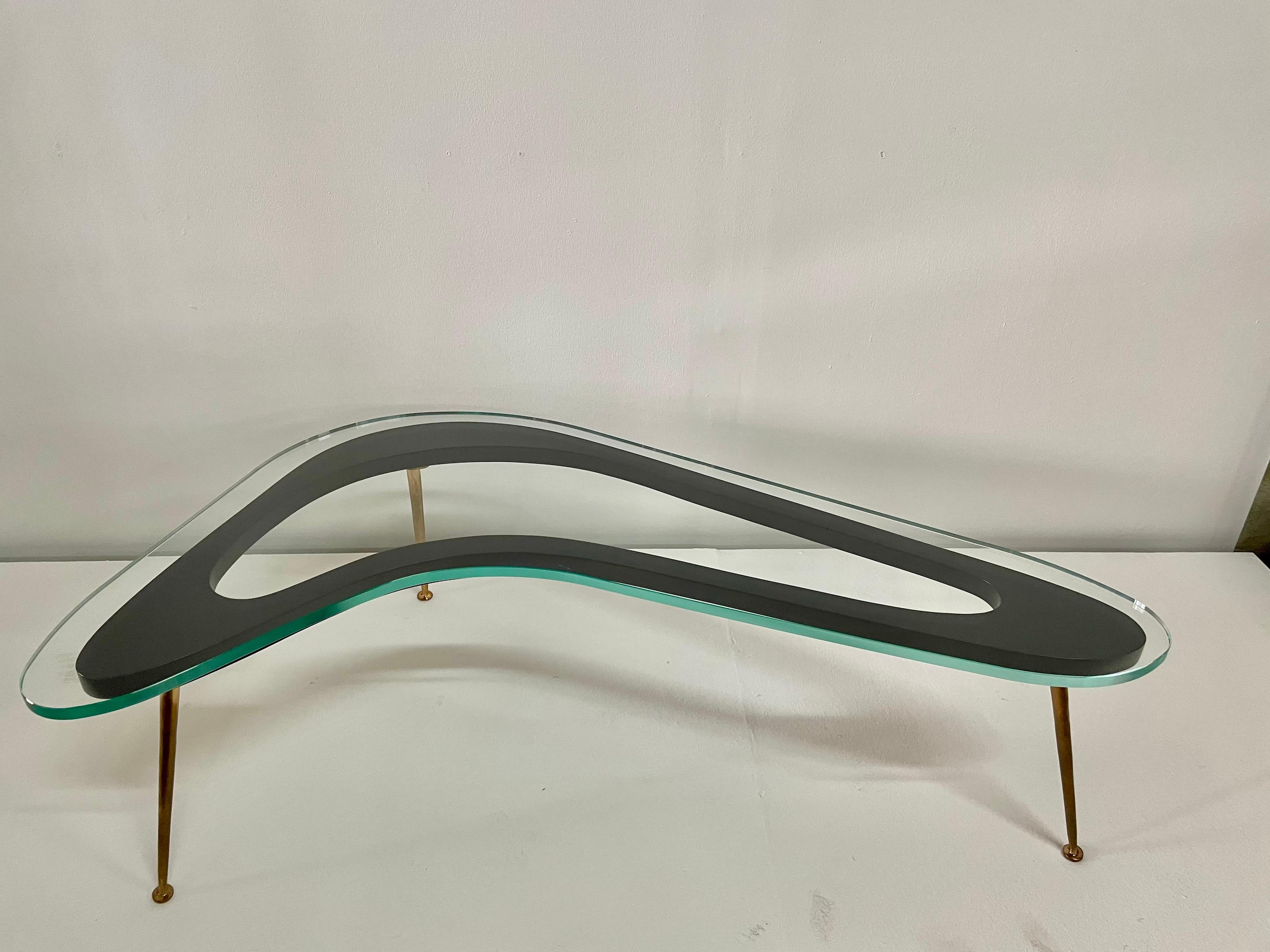 Extra long tapering bronze legs with a stencil cut boomerang top design and a 3/4 inch glass top. This is truly the best of Italian midcentury design. Lacquered wood in matte black under a 3/4 inch thick glass top and sleek and solid bronze legs.