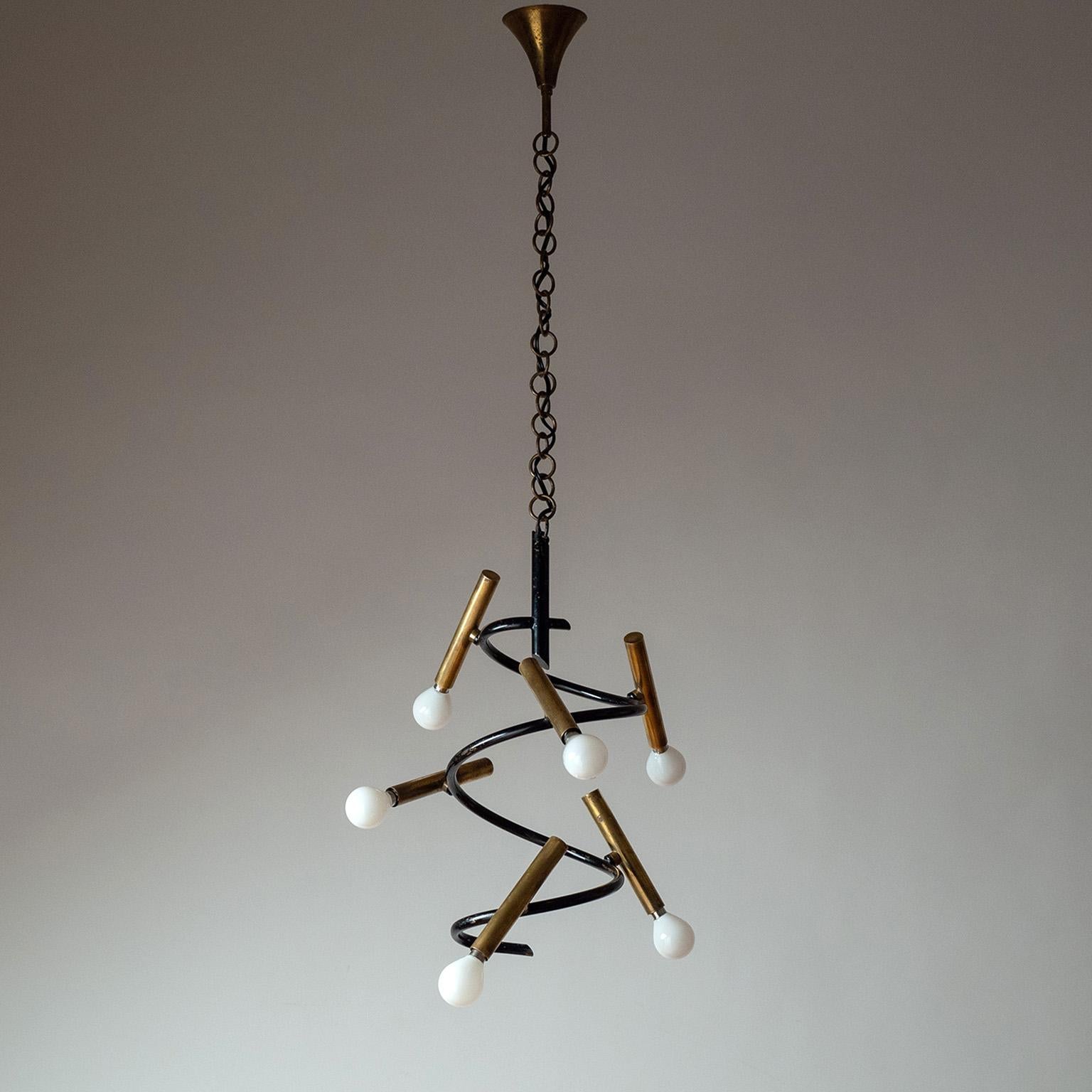 Raro lampadario modernista italiano in ottone degli anni '50. Struttura a spirale laccata nera con sei copriprese tubolari in ottone disposte in posizioni apparentemente casuali. In buone condizioni originali, con una discreta patina sugli elementi