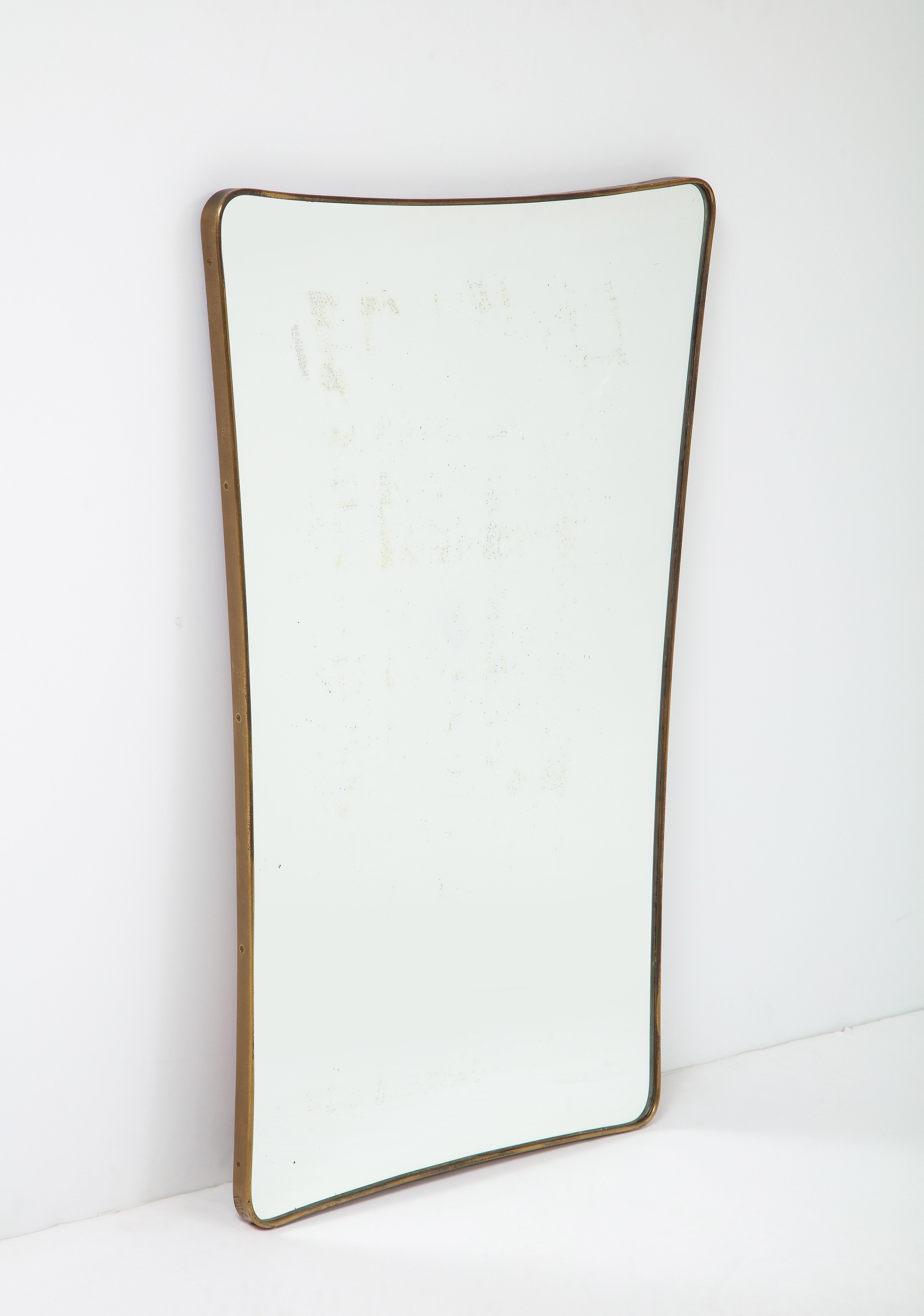 Elegant Italian modernist brass framed mirror with gently curved form, Italy, 1950s. Completely original with beautifully patinated brass frame and some silvering on mirrored glass and solid construction wood backing. 
 