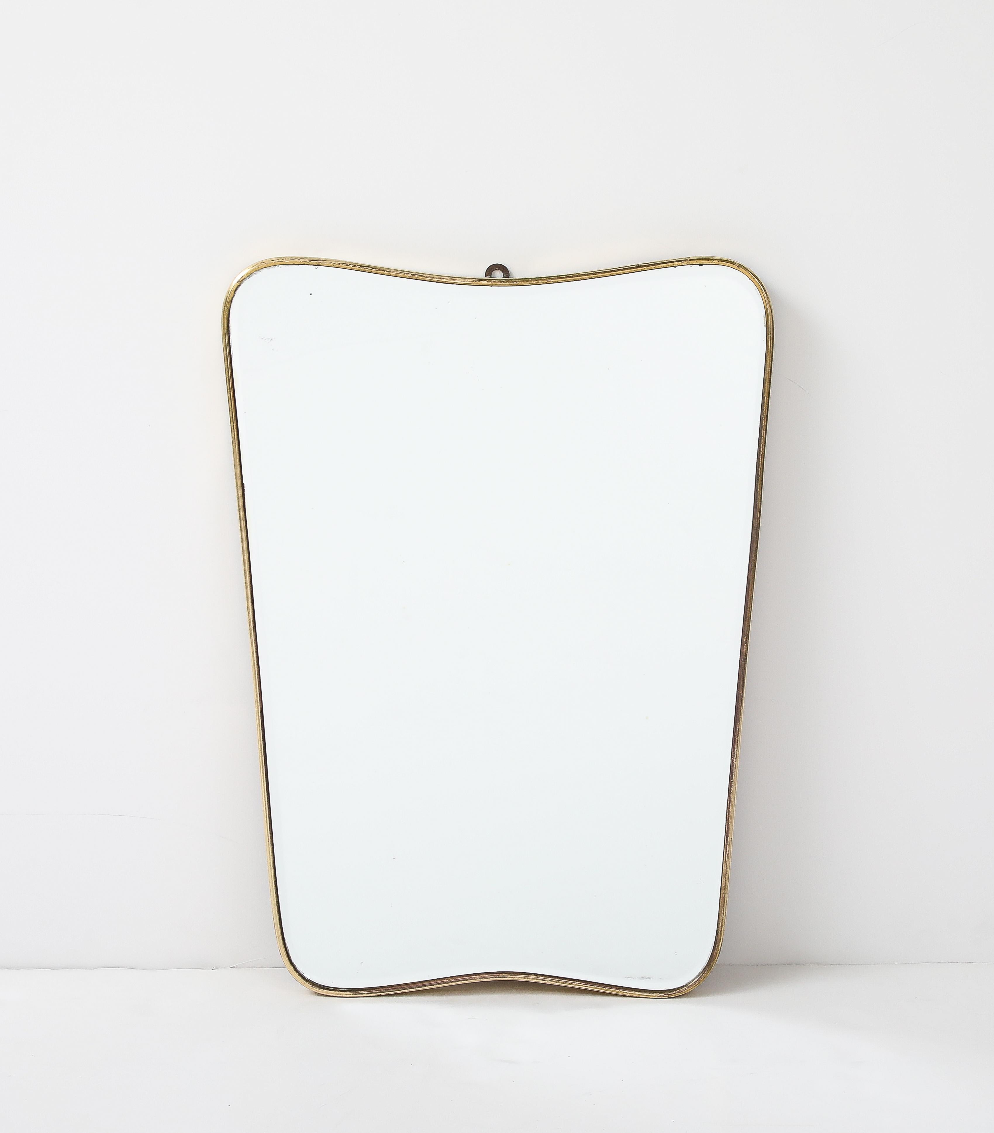 Un beau miroir mural moderniste italien en laiton, avec une magnifique patine du laiton, une plaque de miroir d'origine et un support en bois. 
Italie, vers 1950
Dimensions : 23 3/4