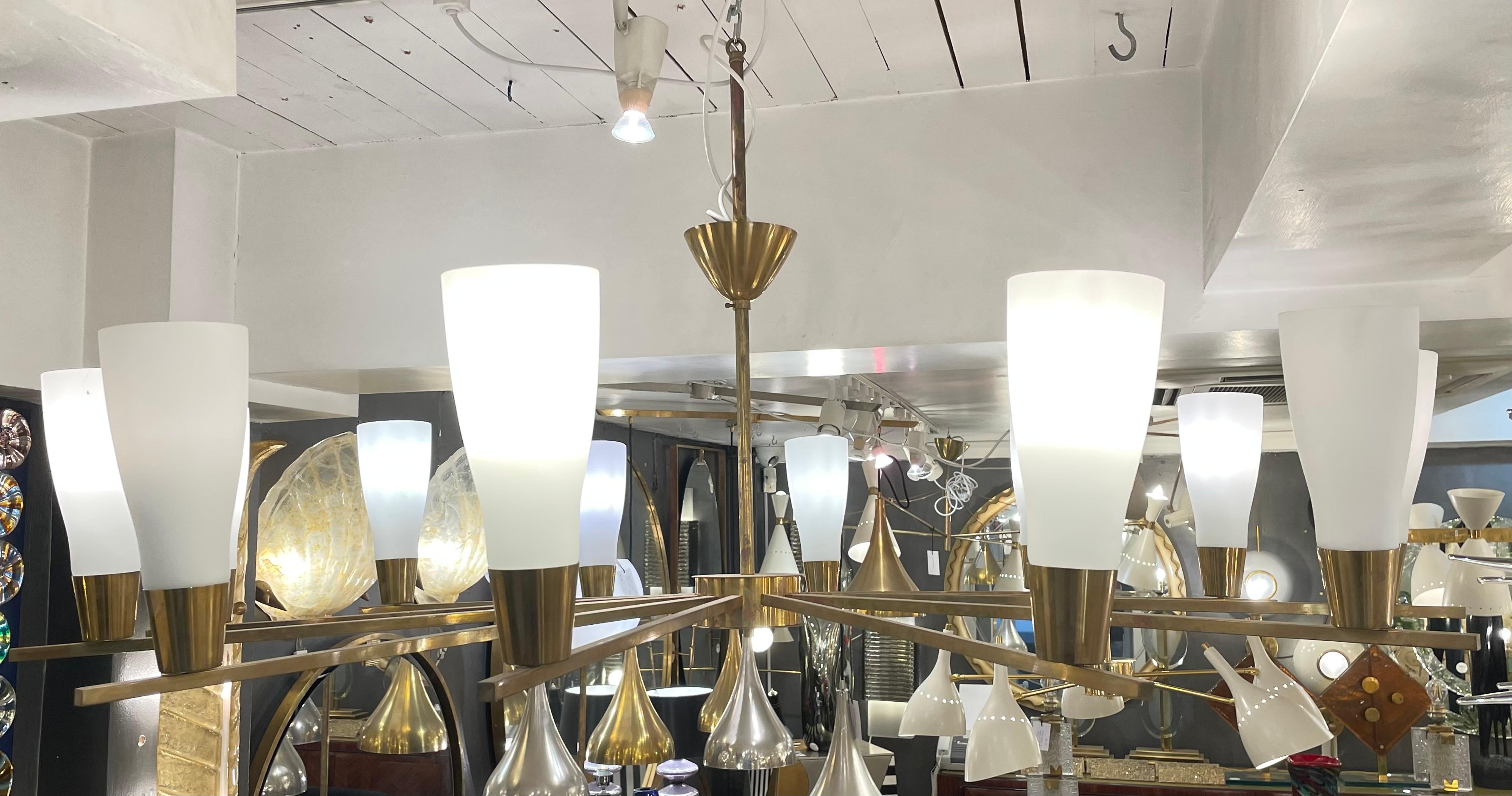A fantastic pair of Italian Modernist Design Chandeliers in brass with 12 arms with white frosted glass shades, circa 1960.