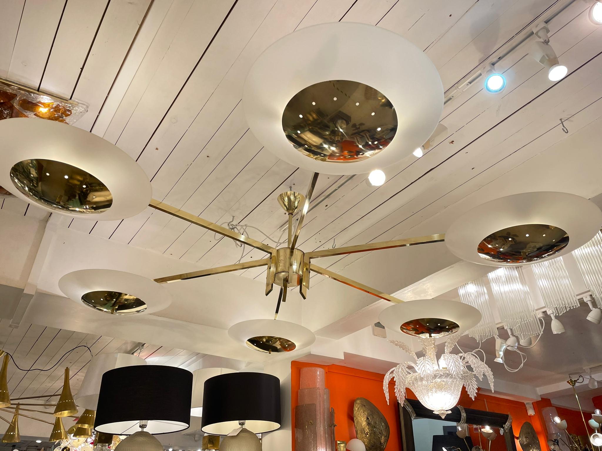 A stunning Italian Chandelier in Brass with 6 arms and white frosted shades. It is an amazing example of 1980s design.
This huge Italian Modernist chandelier chandelier has a brass structure with six arms terminating in large frosted glass and brass