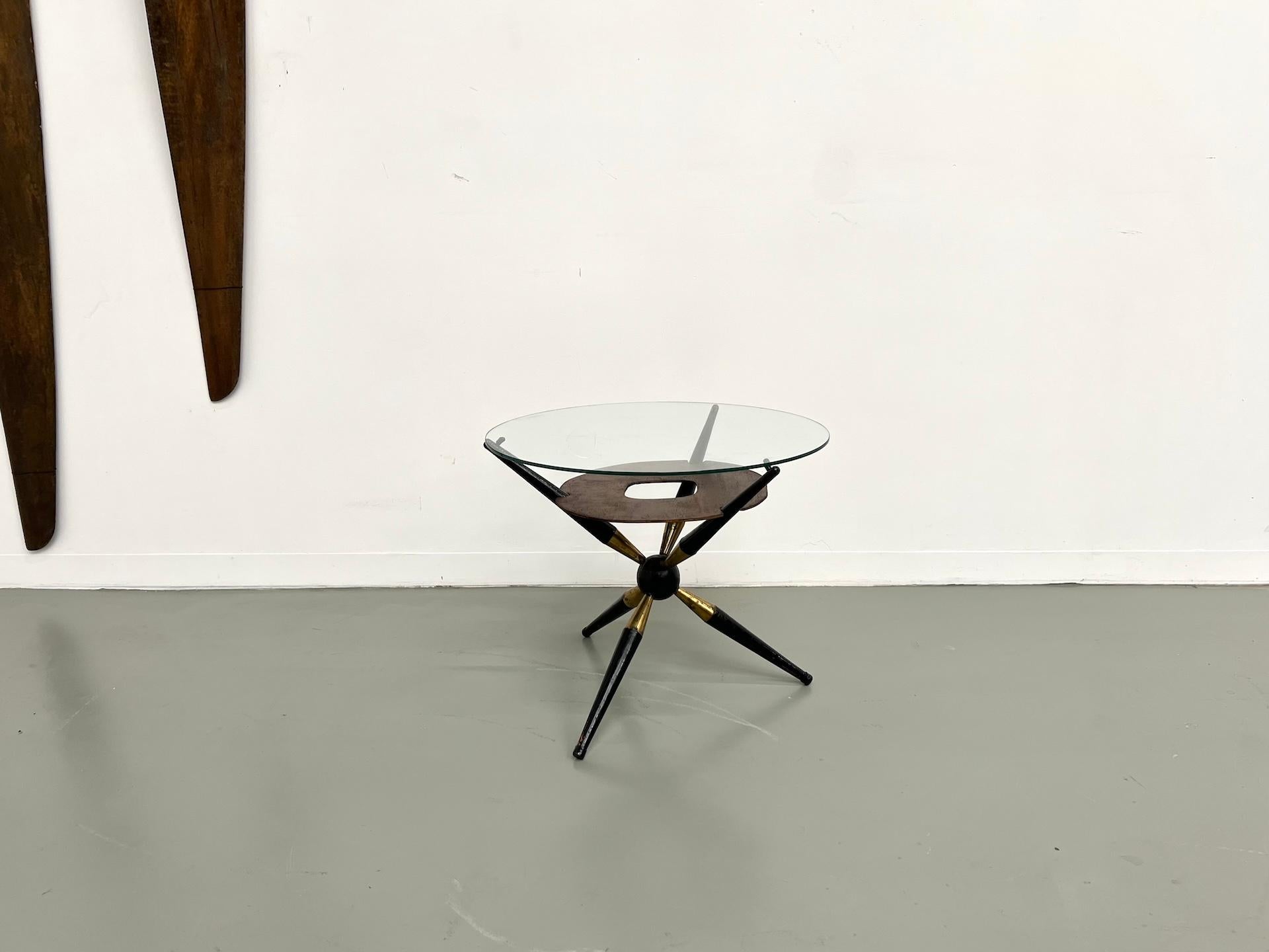 Italian modernist coffee table, 1950s.

Maison Lecan presents this rare tripod coffee table combining wood, brass and glass.

Its sculptural base in ebonized wood and gilt brass supports a circular glass top resting on an elegant perforated plywood