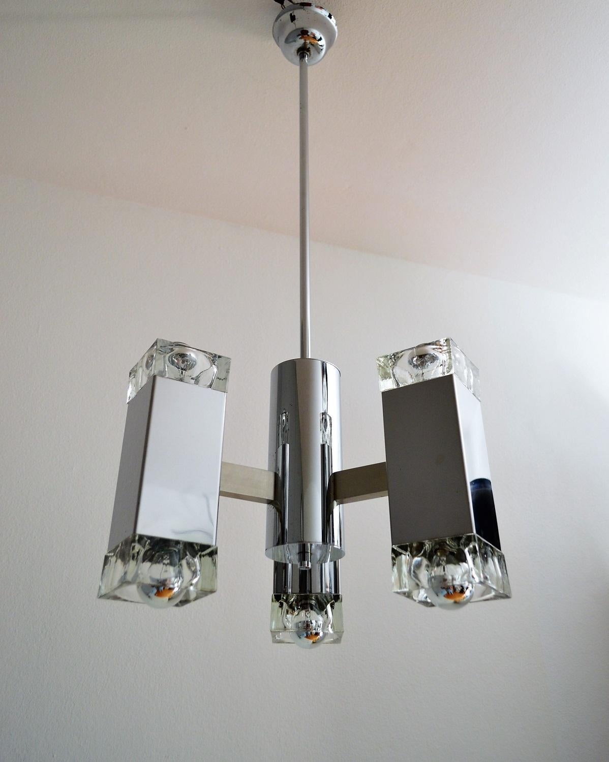 This modernist pendant chandelier, designed by Italian Gaetano Sciolari, is made of chromed metal, aluminium and six heavy cubic glasses ( three-lighting to the top ceiling, three-lighting downwards) , in which fit six small candelabra bulbs