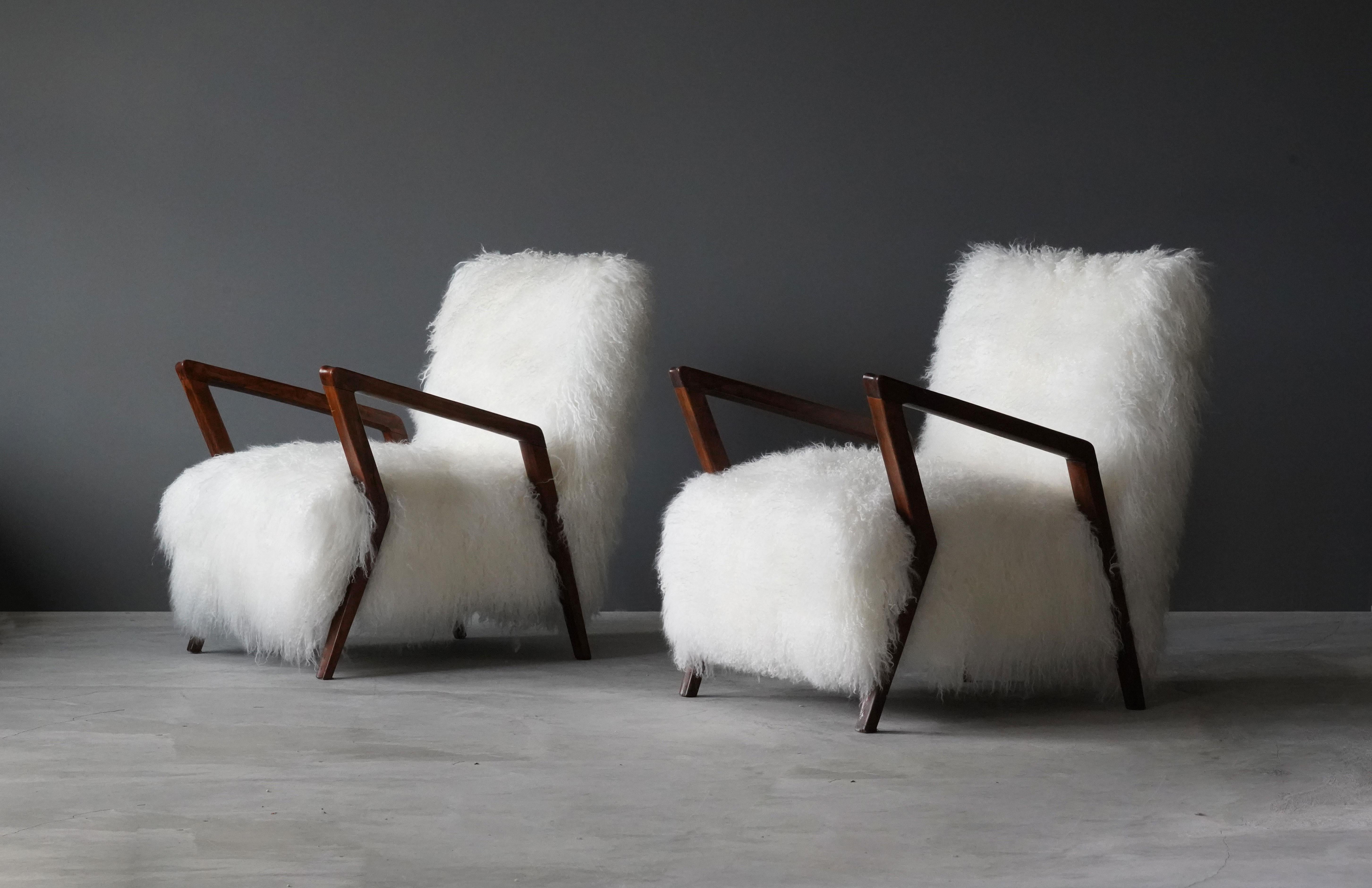 A pair of Italian 1950s lounge chairs / arm chairs. Designer pairs soft overstuffed form with refined carved walnut arms. Reupholstered in brand new sheepskin. Stems from a collection in Turin, Italy. 





 