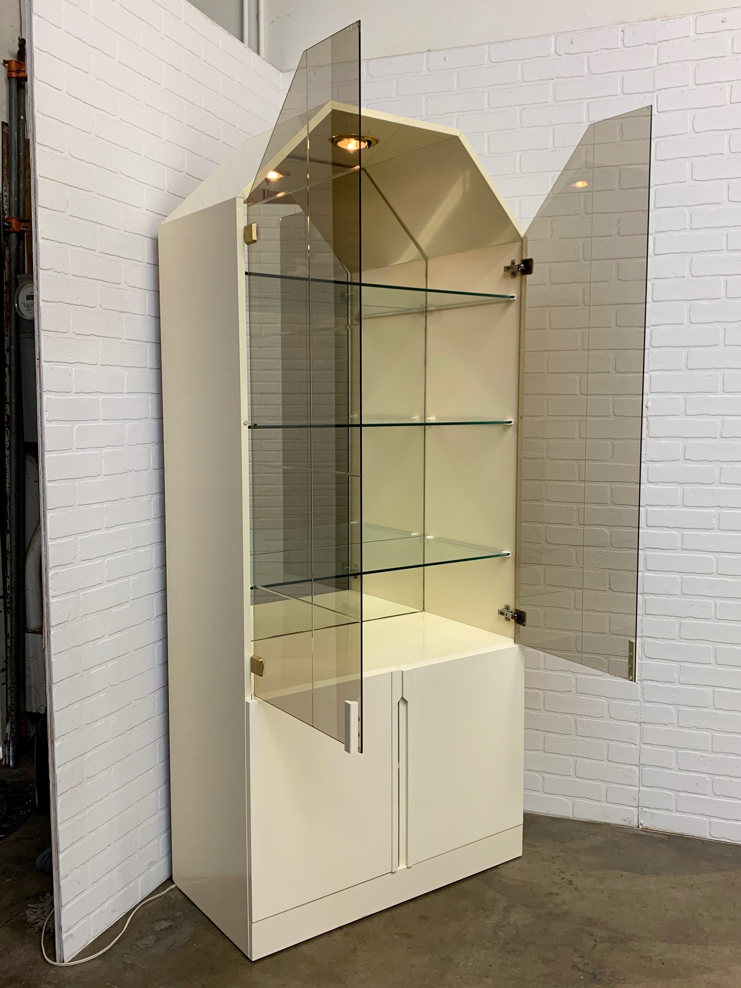 White lacquer Postmodern vitrine with bronze smoked faceted glass and beveled mullions on the glass doors 
with storage down below. Can be used for china, glassware or collections.