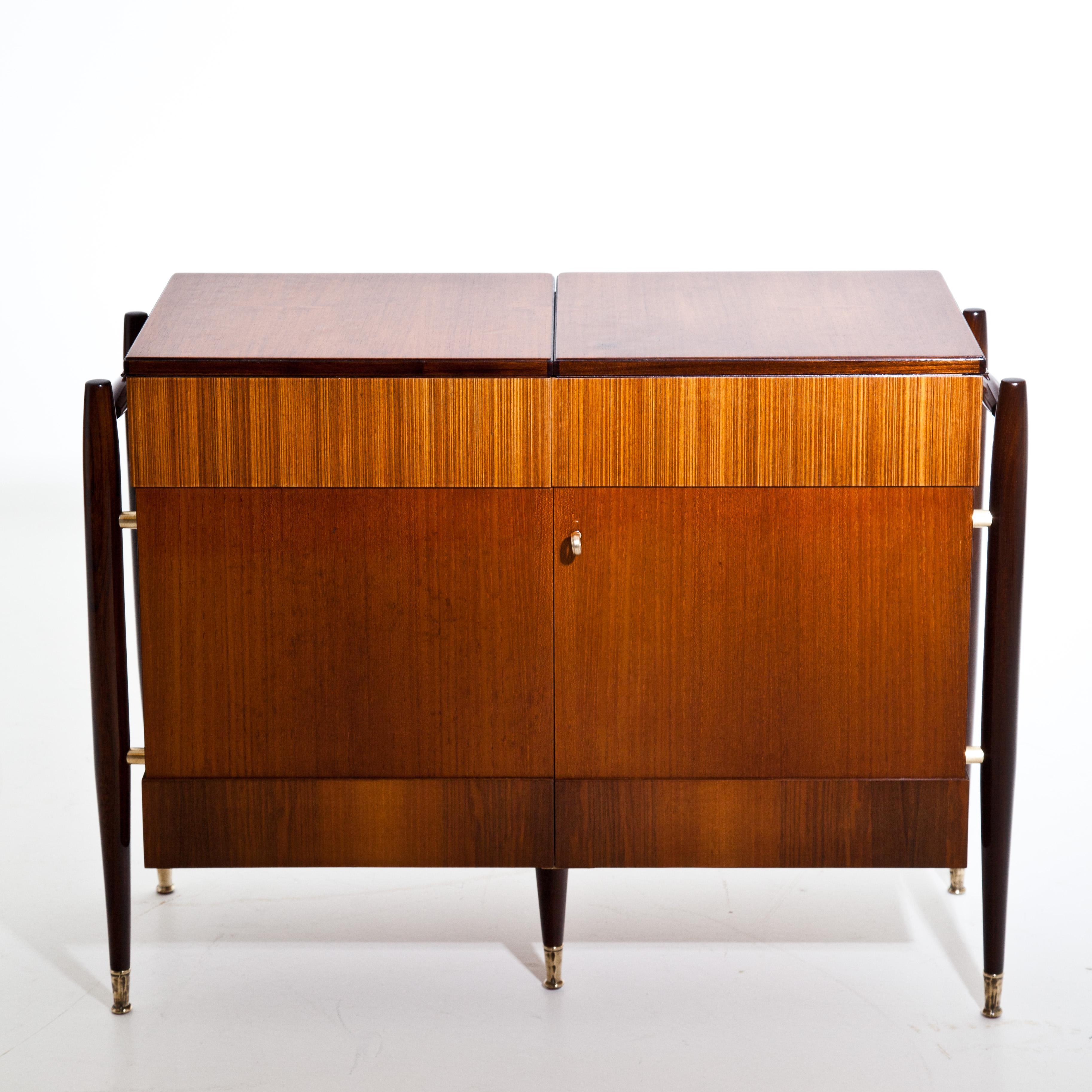 An Italian modernist folding bar cabinet. Bar folds open in the middle and is finished on all sides to be free standing. Mahogany, teak, patinated brass details.
