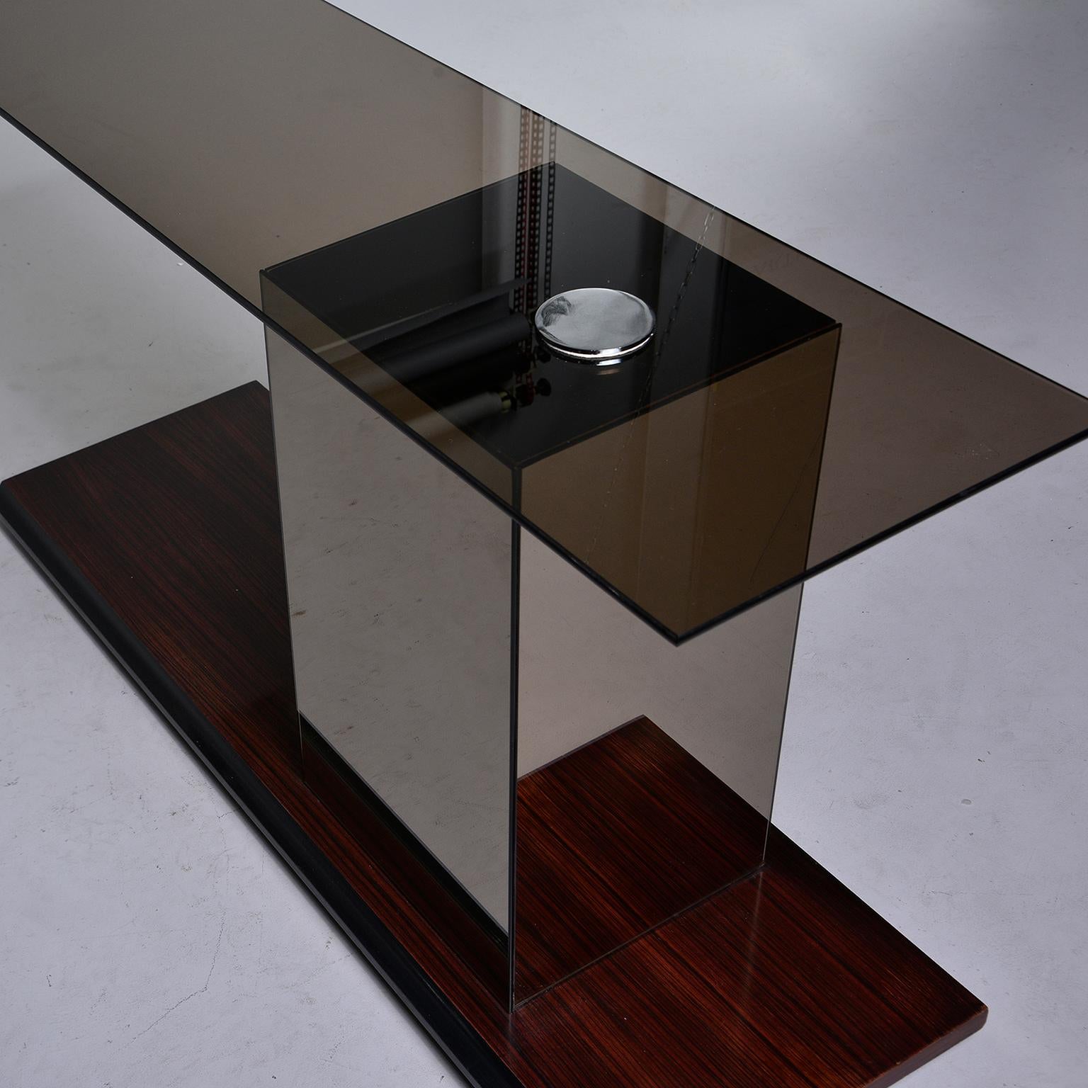Modernist style Italian console features a walnut base, mirrored off-center support and smoke colored glass tabletop affixed with chrome disk, circa 1970s. Unknown maker.