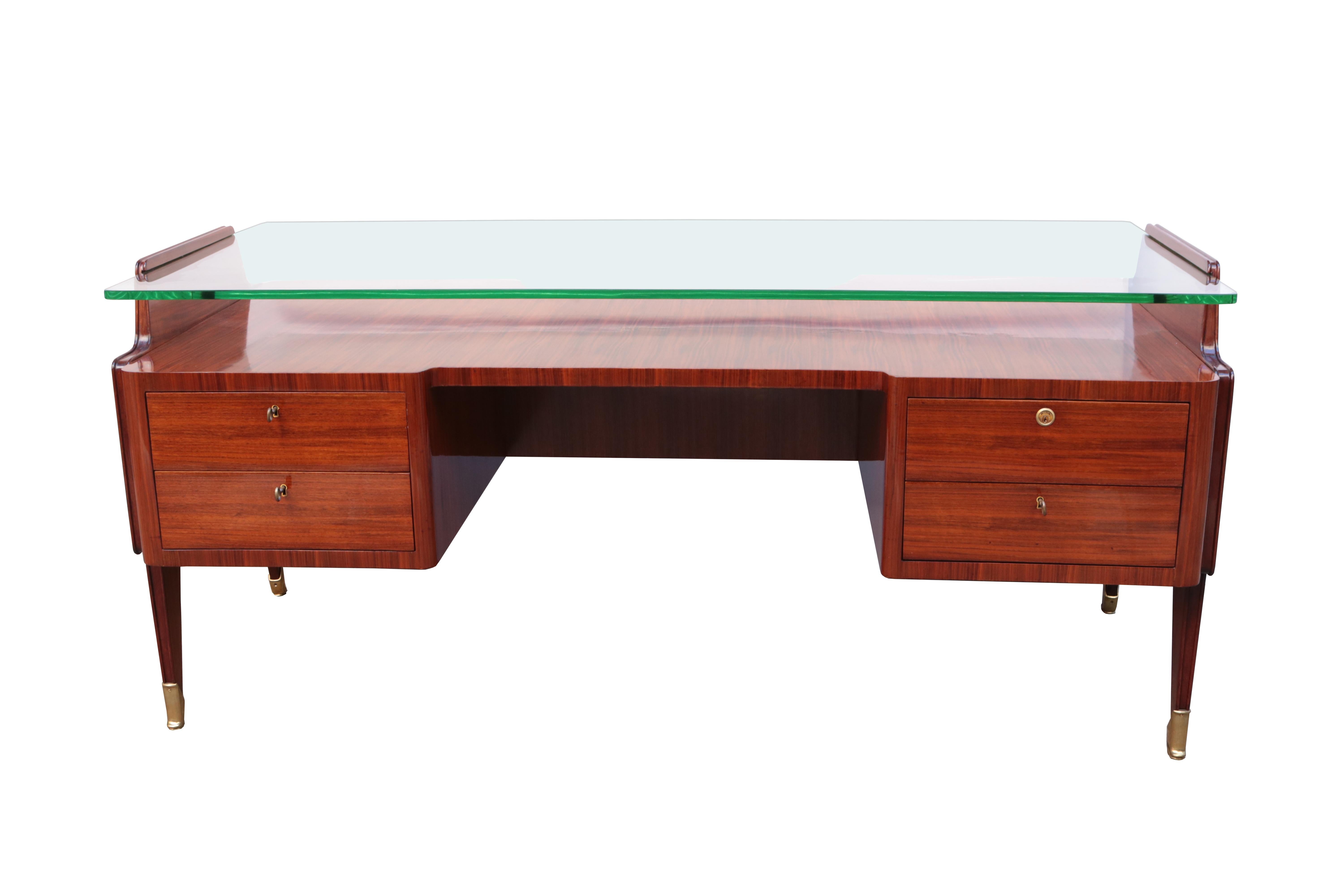 Ein italienischer modernistischer Schreibtisch mit Glasplatte. 
Mahagoni mit Fruchtholzintarsien, patinierte Messingsäbel, originale Glasplatte.