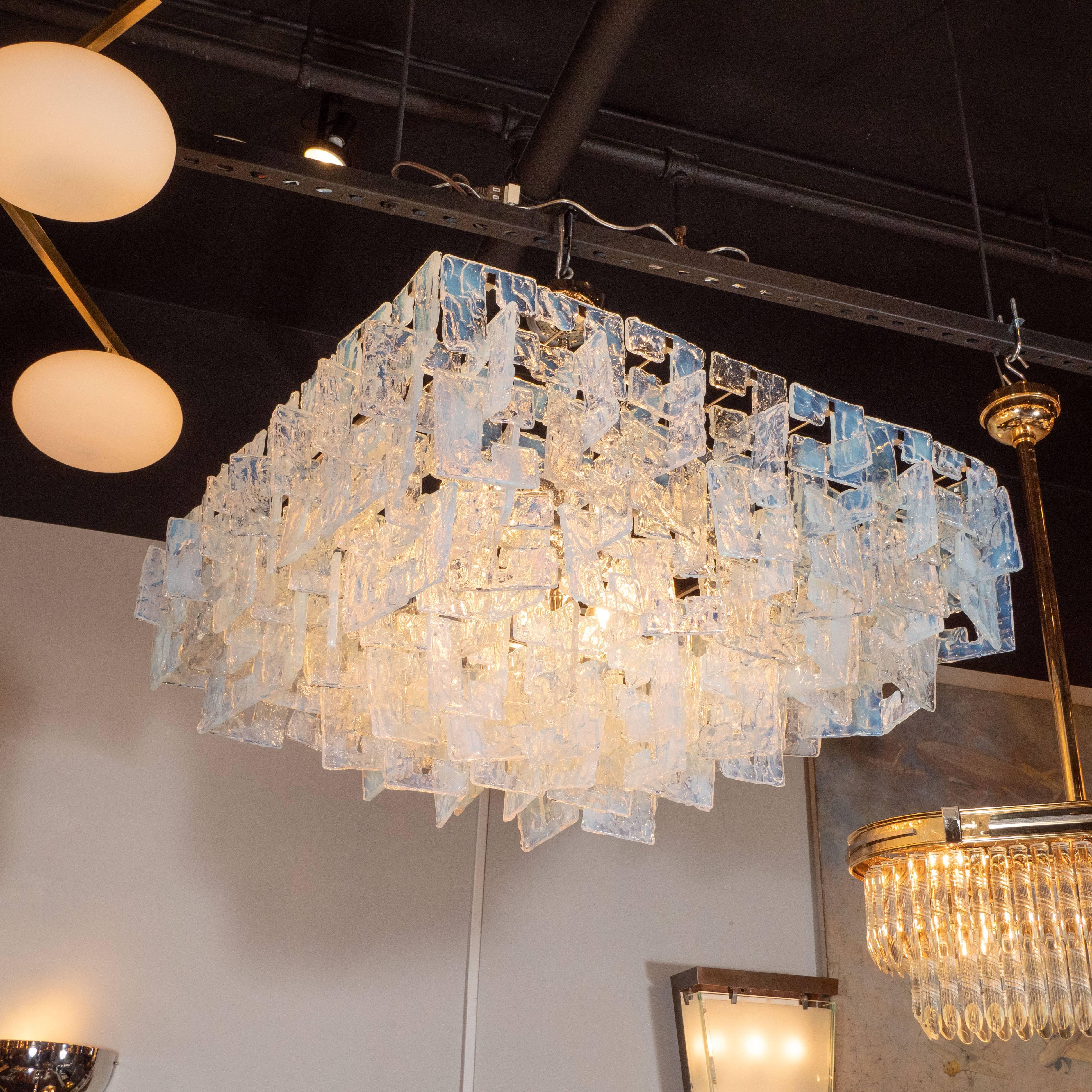 This stunning and graphic modernist chandelier was realized by our custom atelier in Murano, Italy. It features an abundance of interlocking three-sided translucent square shades with a subtle iridescence and inflections of sky blue connected to a