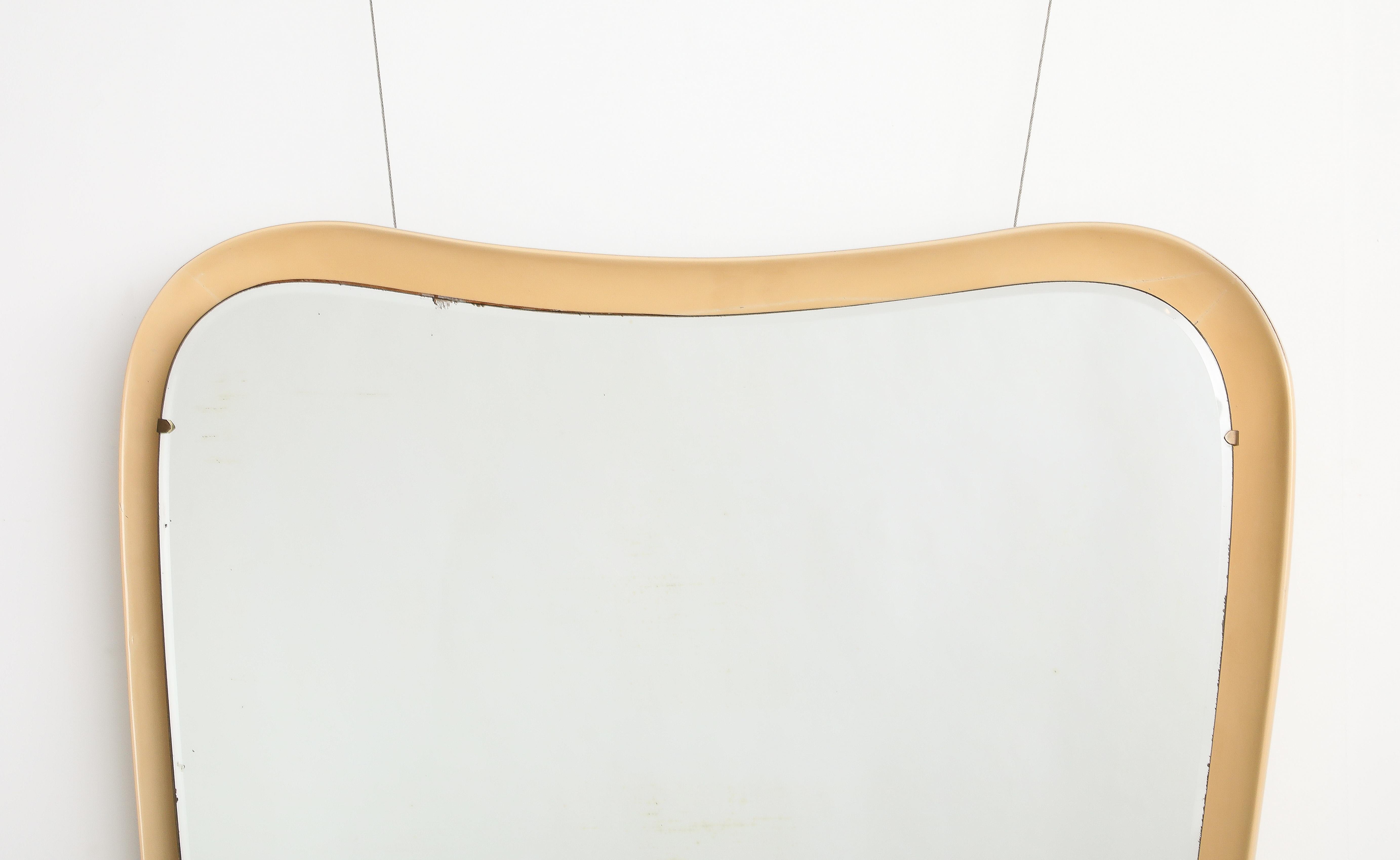 Miroir flottant moderniste italien de grande taille et très unique ; la plaque de miroir biseautée est soutenue par un cadre moulé laqué de couleur crème ; le dessus arqué avec des coins arrondis se rétrécit vers l'arrière.  base.  Une image
