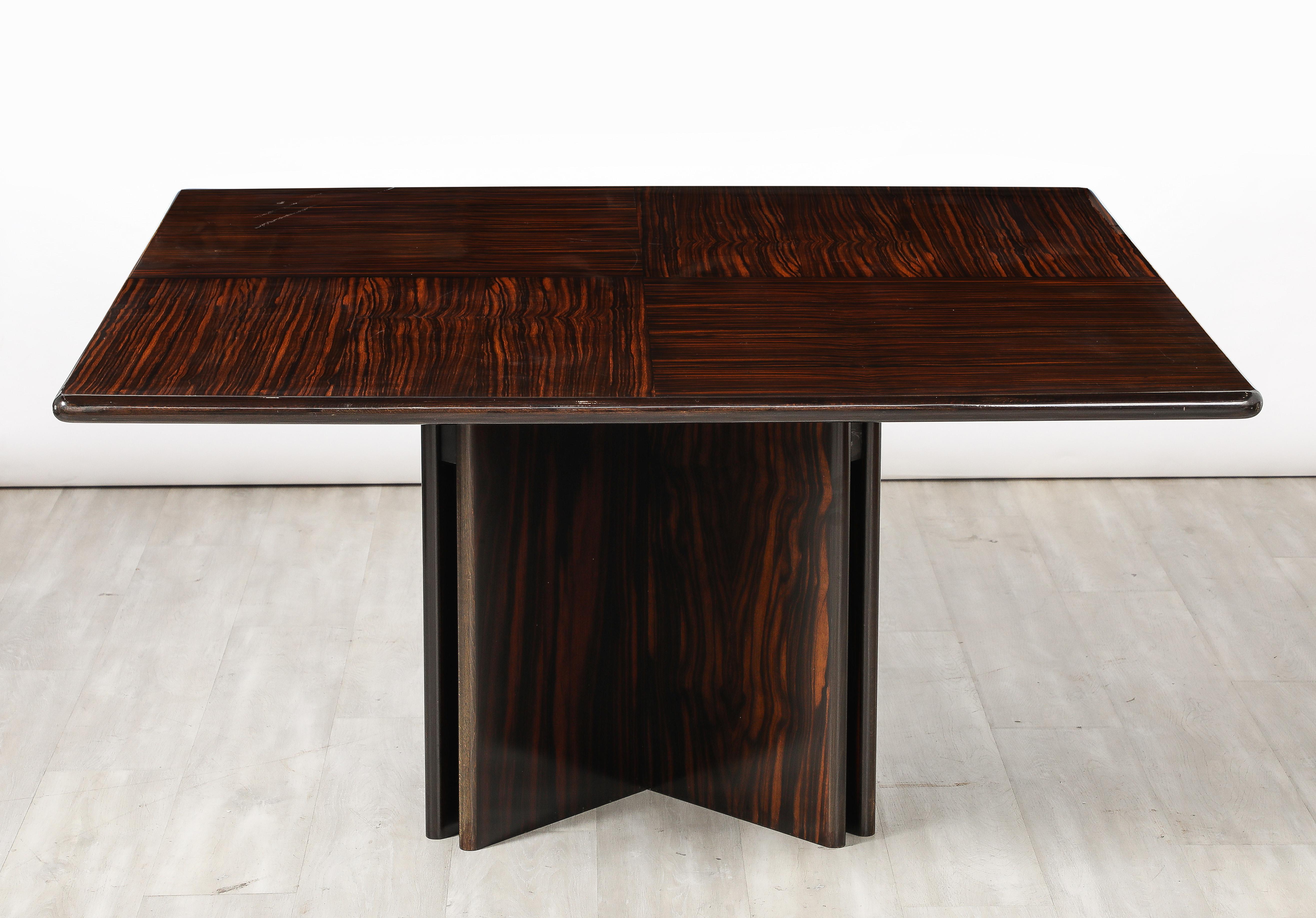 An Italian modernist dining table in Macassar ebony; the large square surface is supported on four bases.  A grand and glamorous statement piece.  Seats 8 and up to 12 comfortably.  The top is coated in acrylic and can be used conveniently for